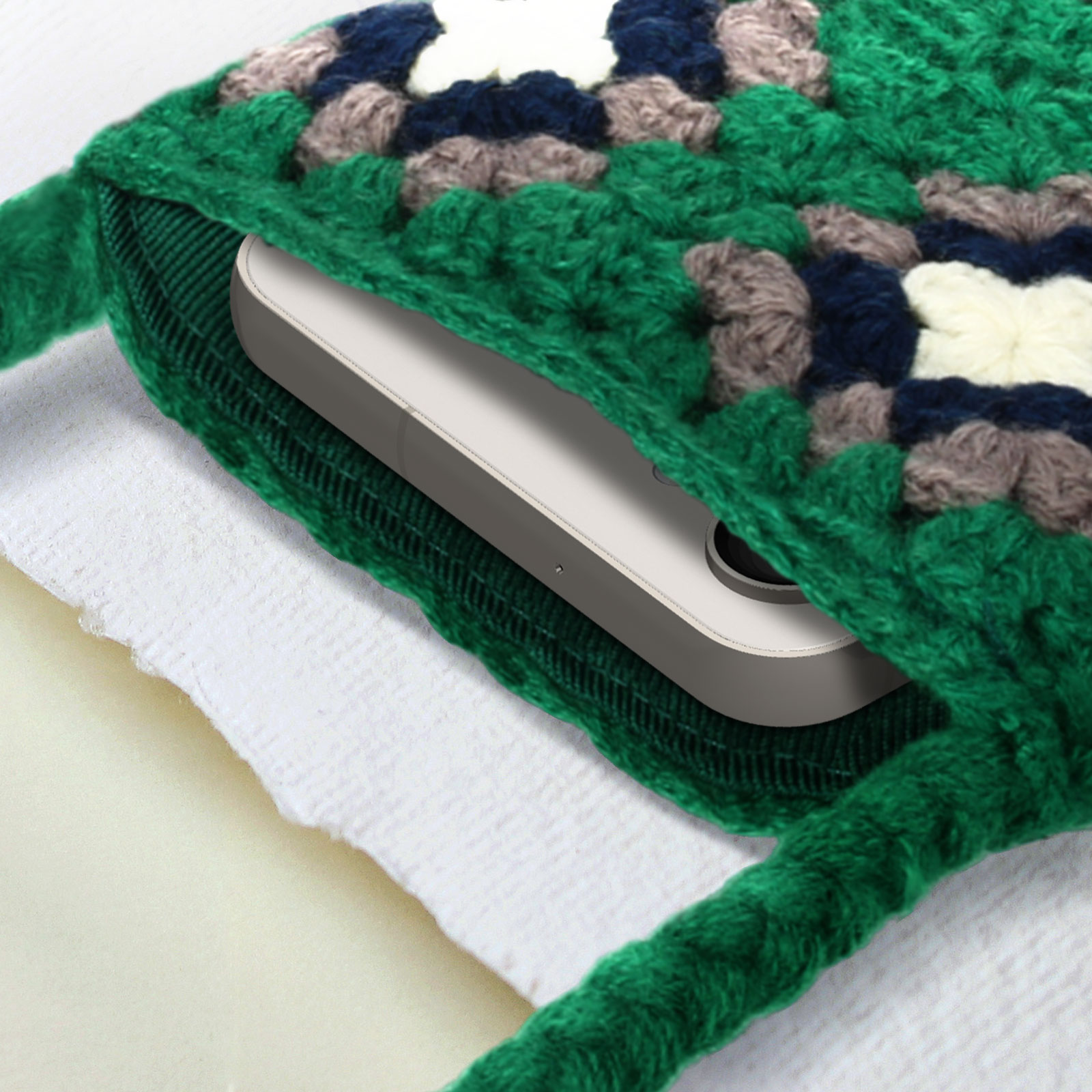 Borsa verde all'uncinetto, che tiene un telefono. La borsa è parzialmente aperta.