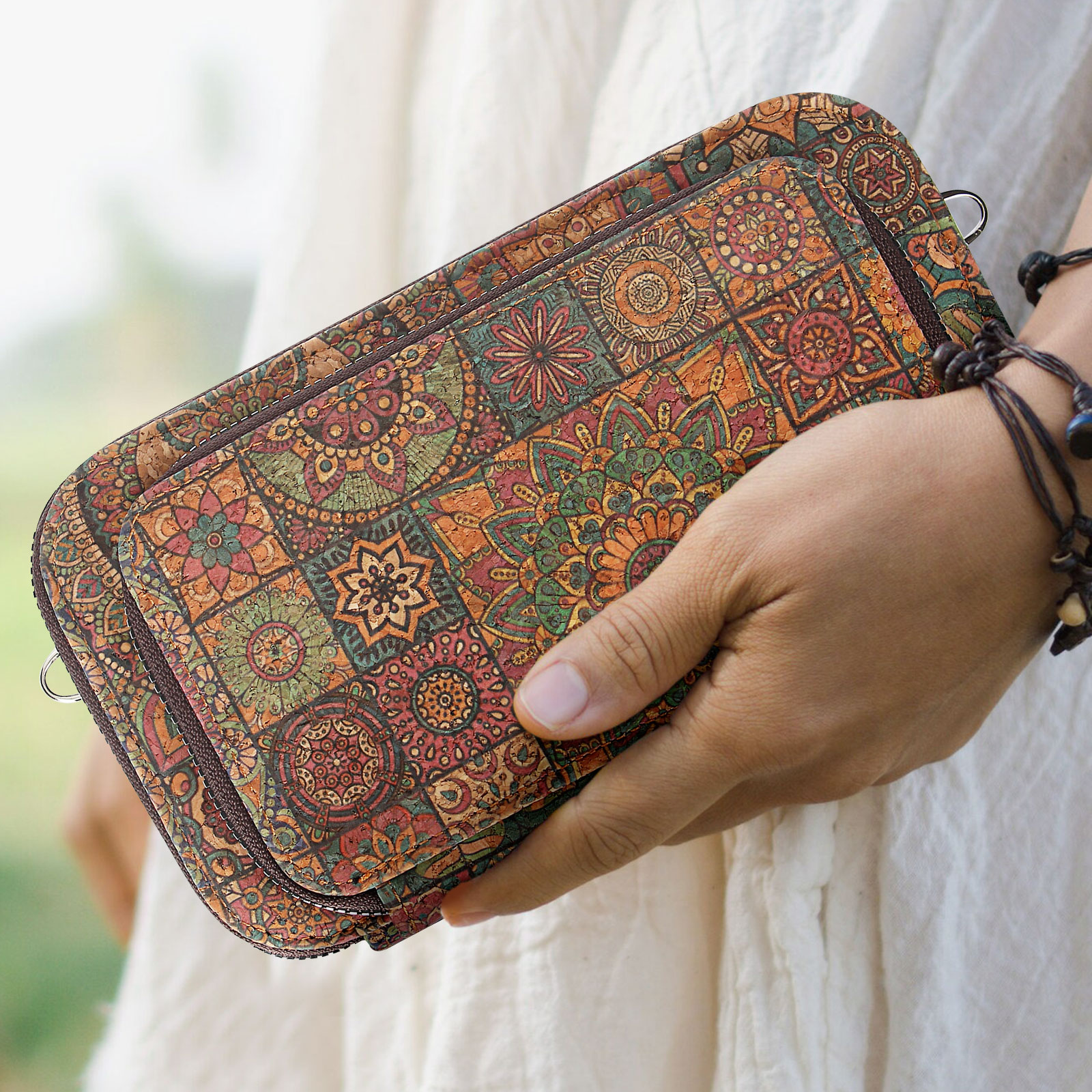 Eine Person hält eine gemusterte Tasche. Die Tasche hat ein Blumendesign und einen braunen Reißverschluss.