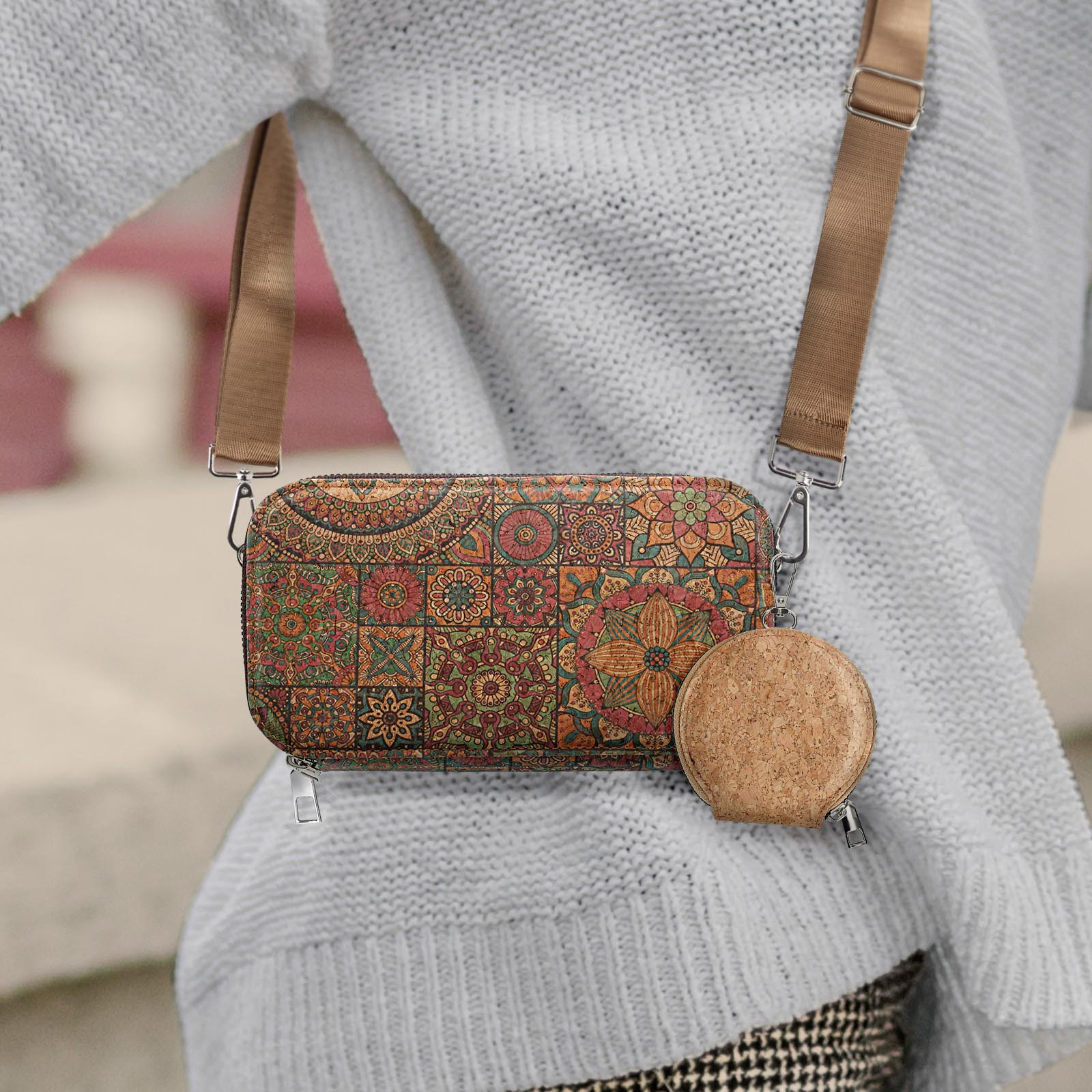 Eine Frau in einem weißen Pullover hält eine gemusterte Tasche mit Umhängeriemen.