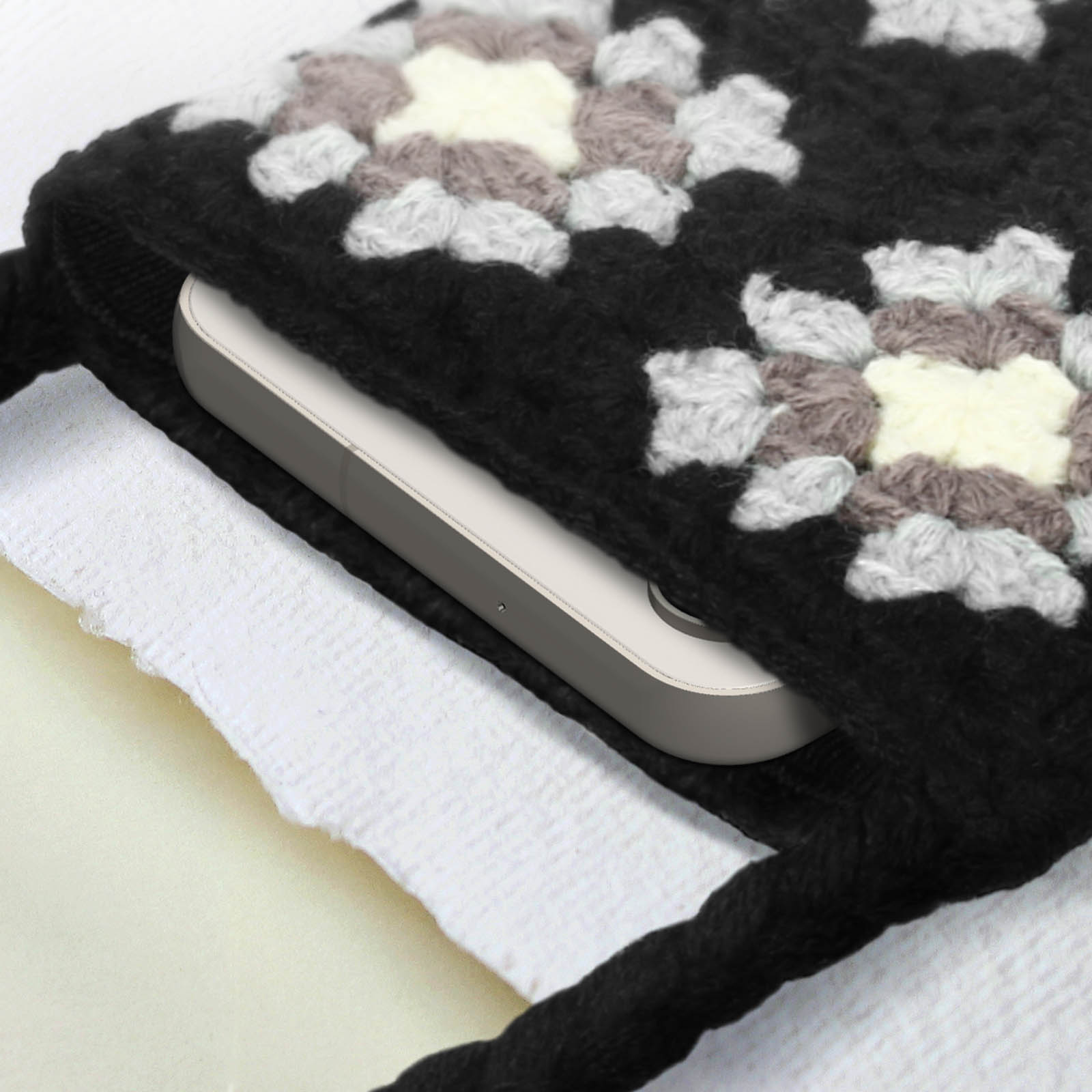 Una custodia in maglia bianca e nera, con un telefono parzialmente visibile all'interno.