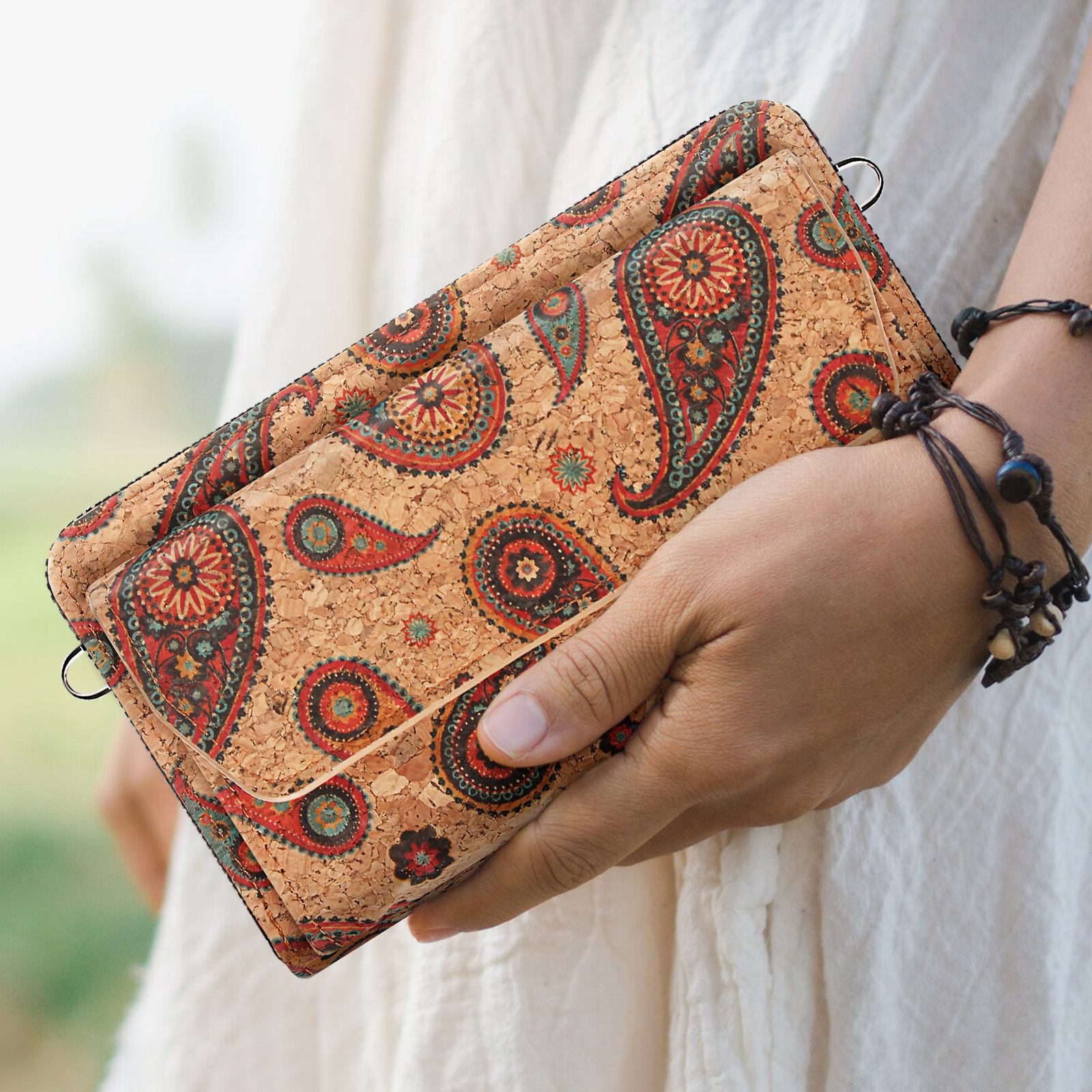 Eine Person hält eine Korkbrieftasche mit Paisley-Muster.