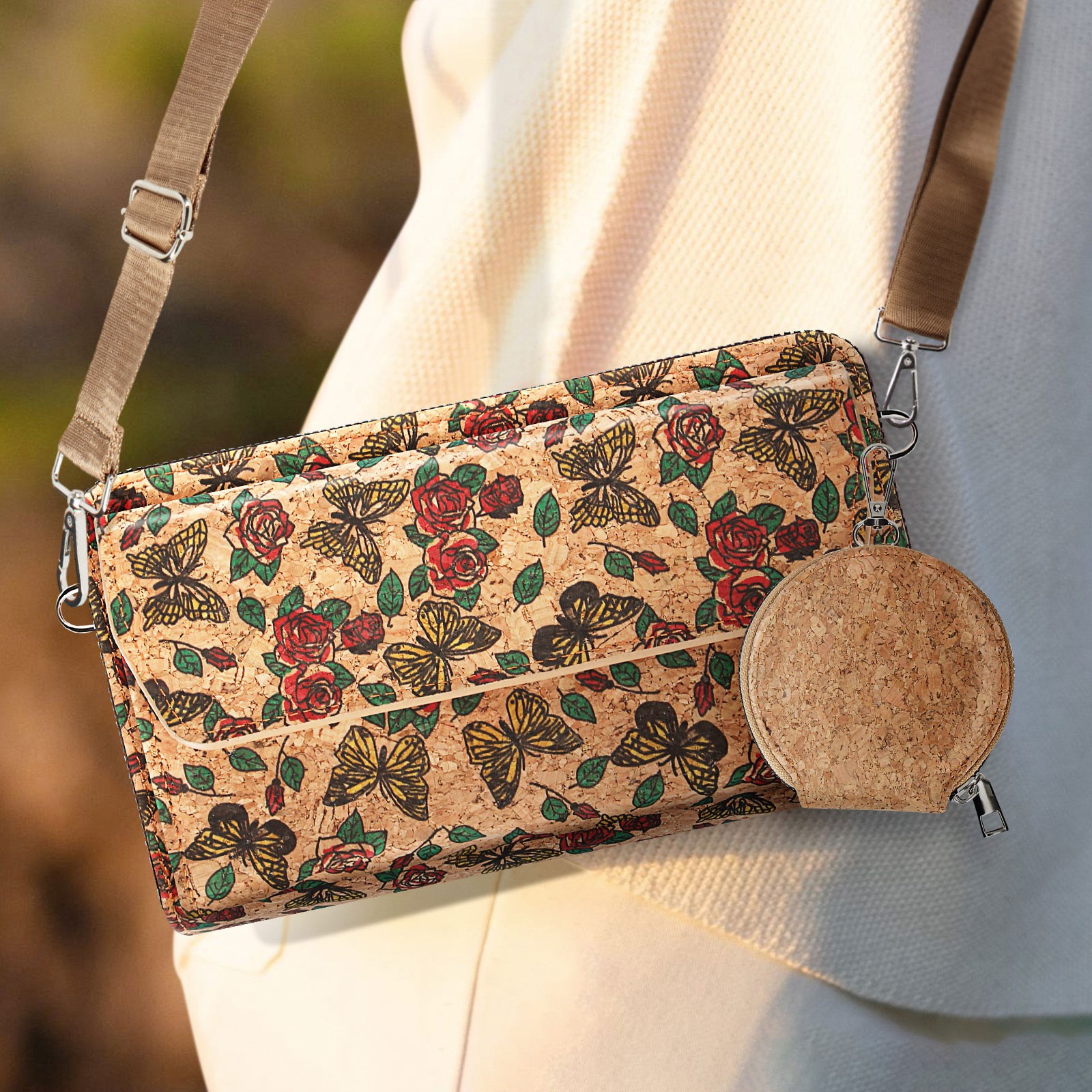 Eine Handtasche mit Schmetterlings- und Rosenmuster, gehalten von einer Person mit weißem Pullover.