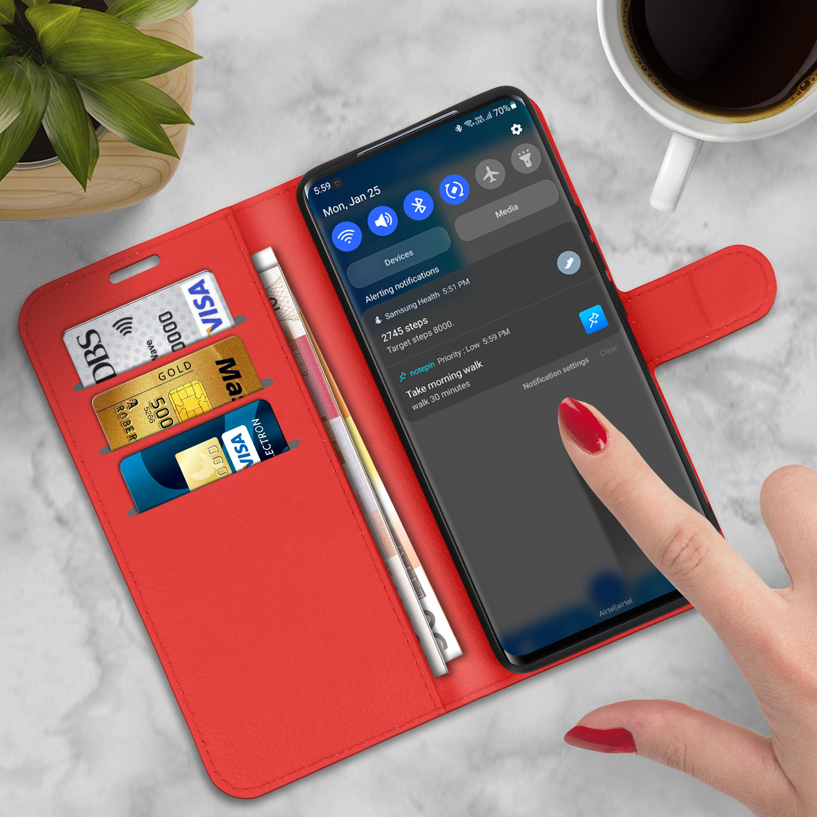 Portafoglio rosso aperto con telefono, carte e una mano con unghie rosse.
