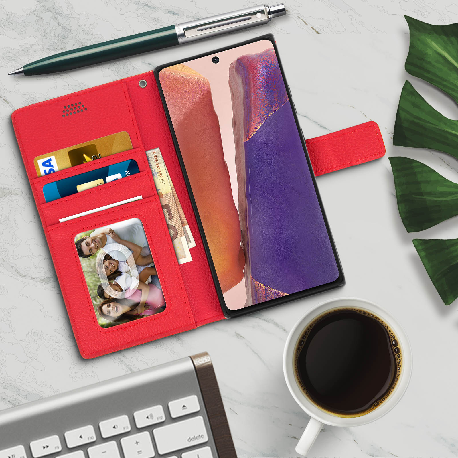 Custodia rossa con carte, foto e denaro. Caffè, tastiera e foglie sul tavolo.