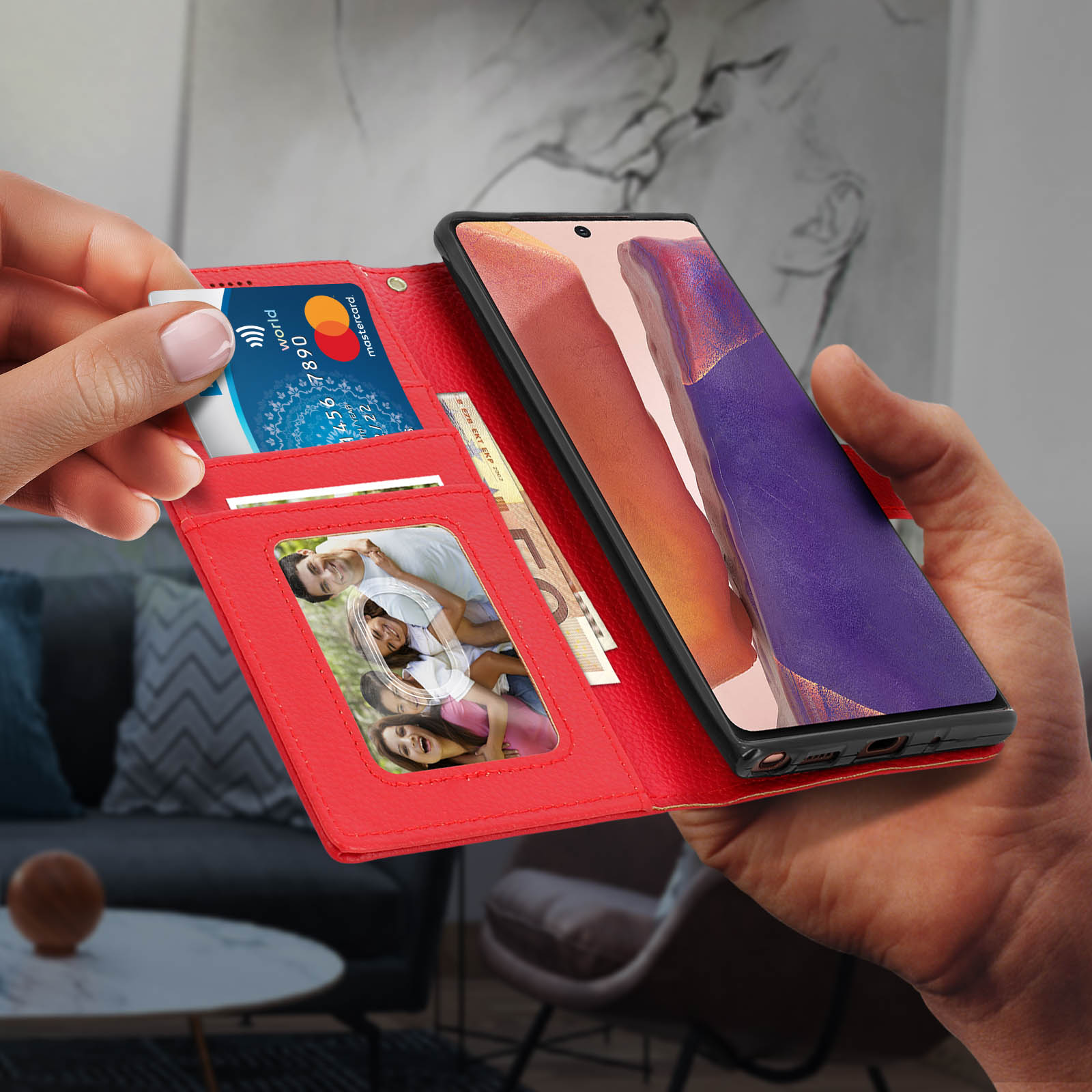 Mano che tiene un portafoglio rosso con carta e foto, altra mano che tiene un telefono.