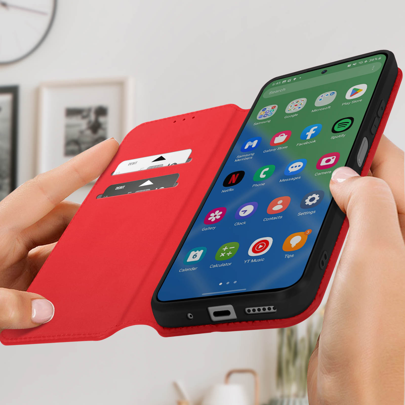 Mani che tengono una custodia rossa con un telefono dentro. Schermo del telefono visibile. Vengono visualizzate molte app.