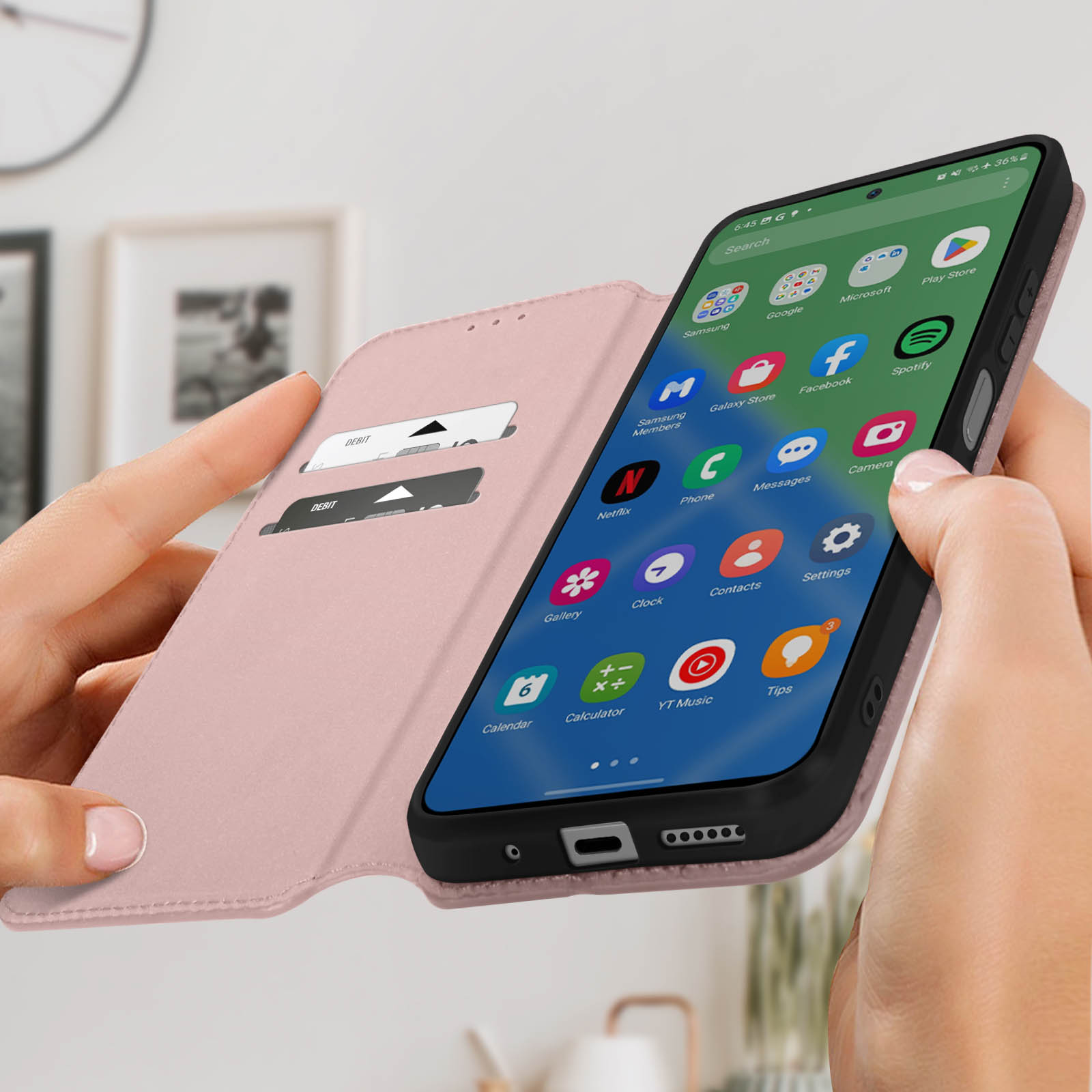 Un teléfono en una funda tipo cartera rosa. El teléfono muestra una pantalla de inicio con aplicaciones.