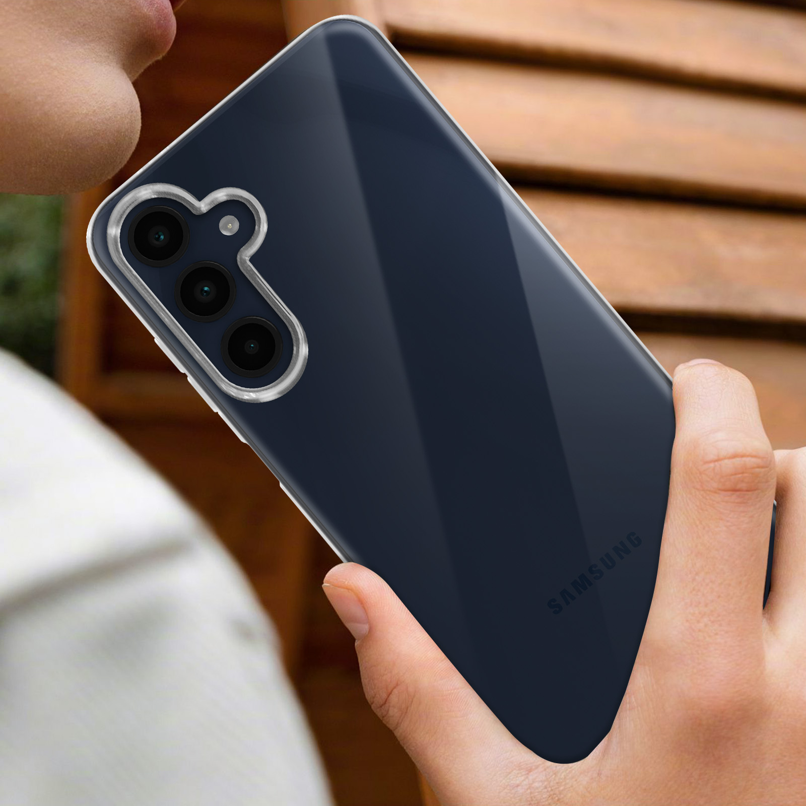 Una mano che tiene un telefono con una custodia trasparente. Il telefono è nero e ha più fotocamere.