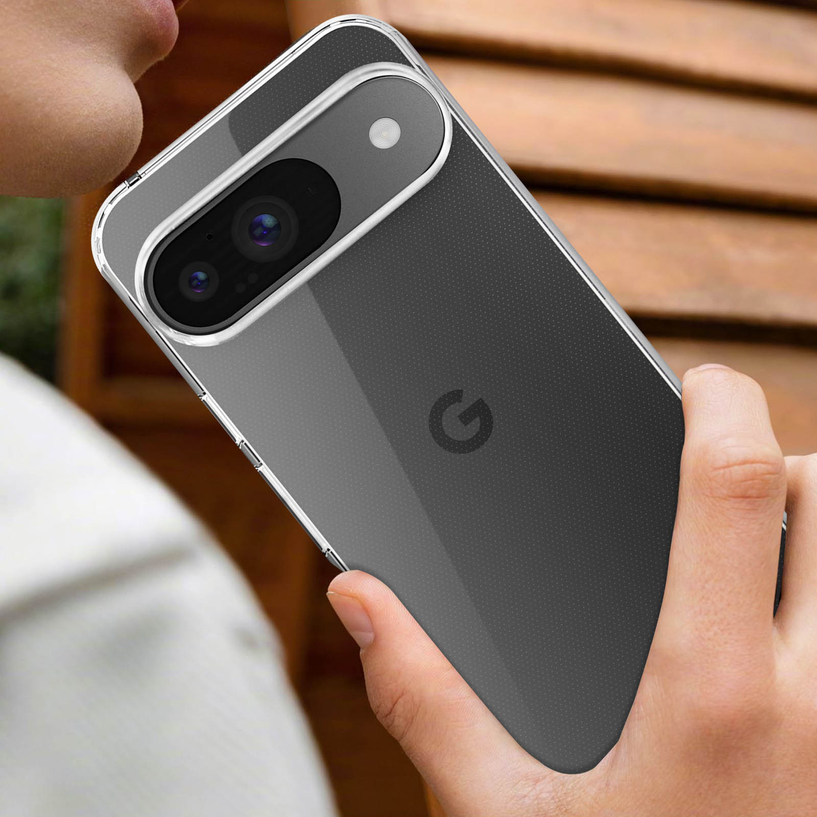 Telefono in custodia trasparente, tenuto da una persona. Il telefono è grigio scuro.