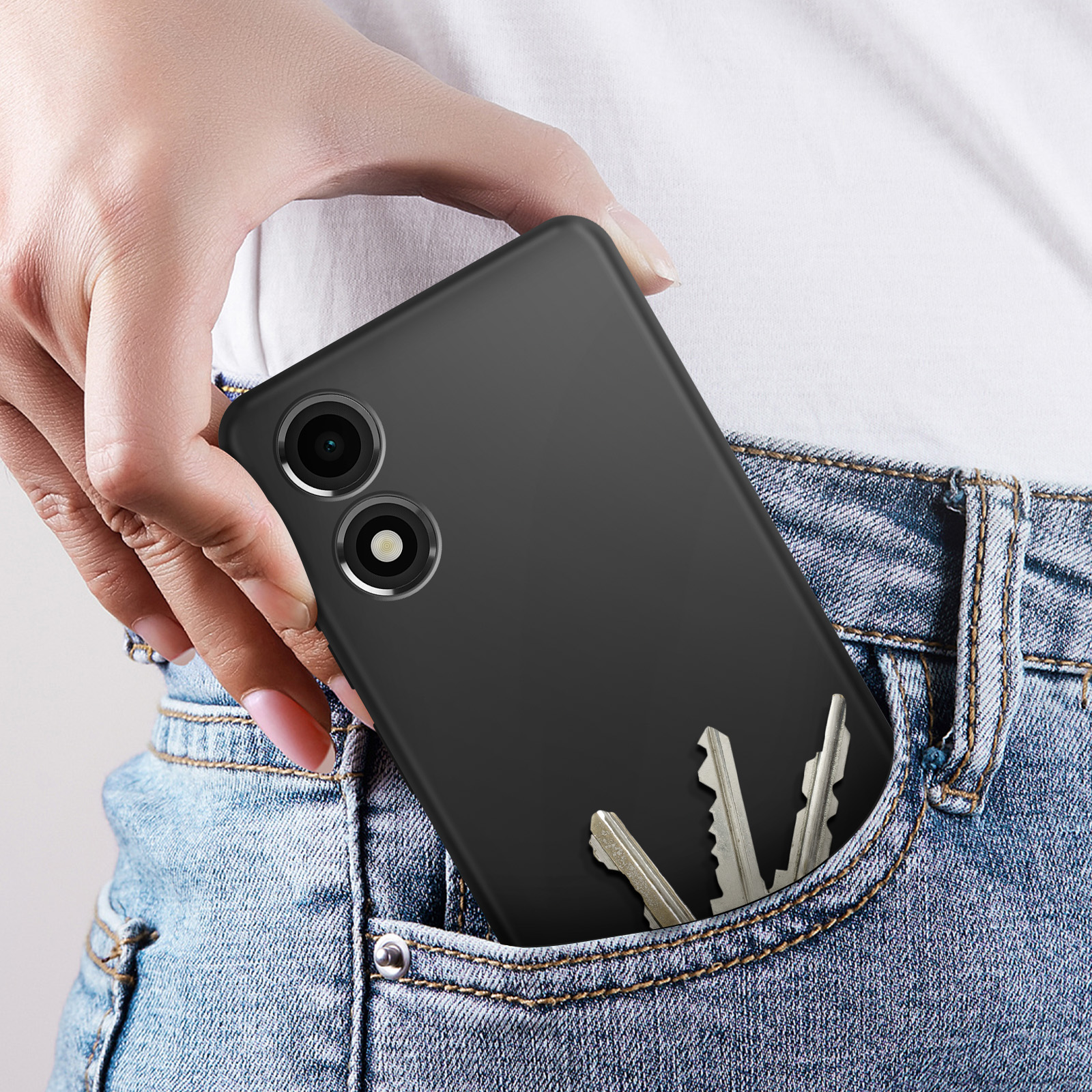 Un telefono nero in tasca con chiavi. Una mano tiene il telefono in una tasca di jeans blu.