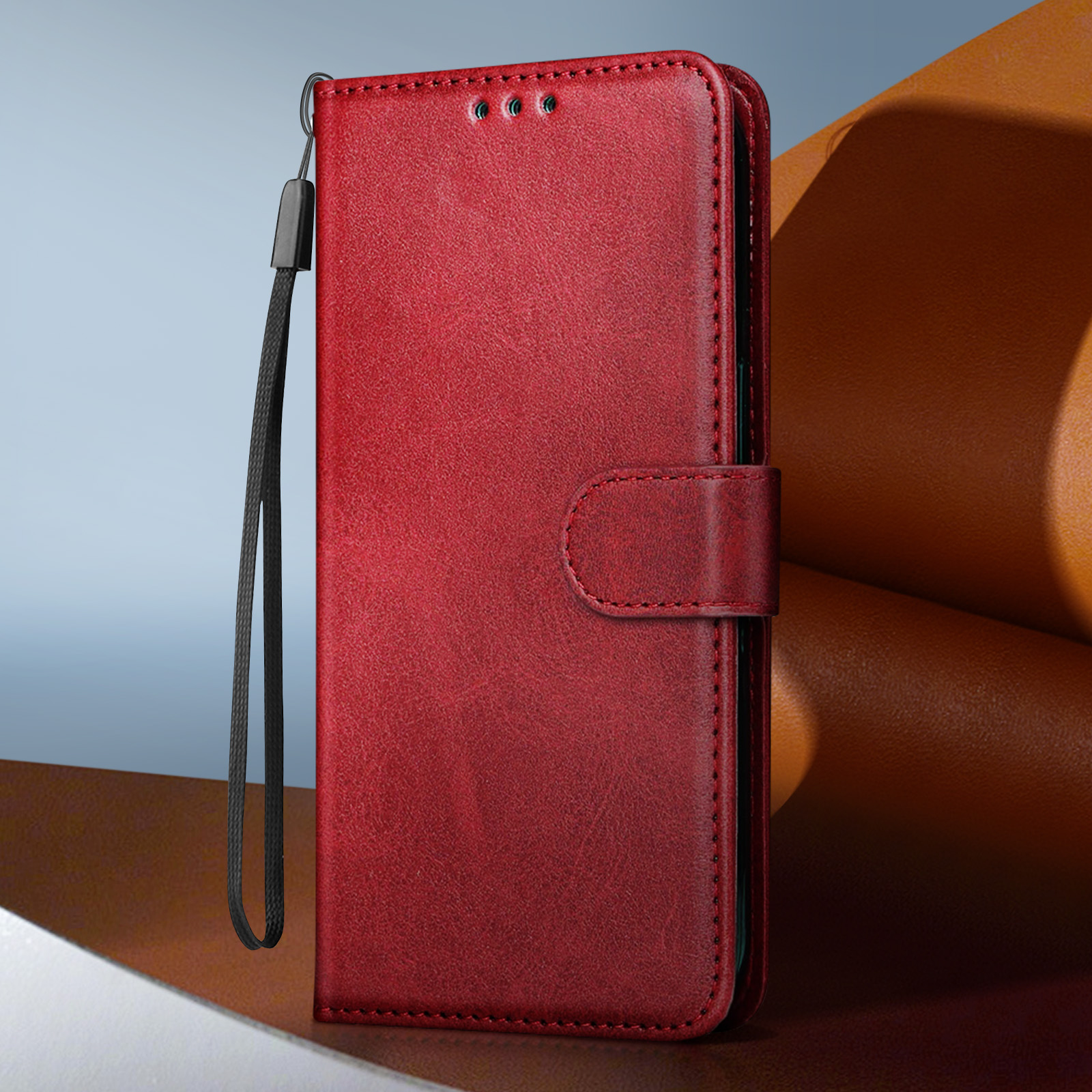 Custodia per telefono in pelle rossa con cinturino. Sfondo rosso. Cinturino nero. Chiusura con fibbia.