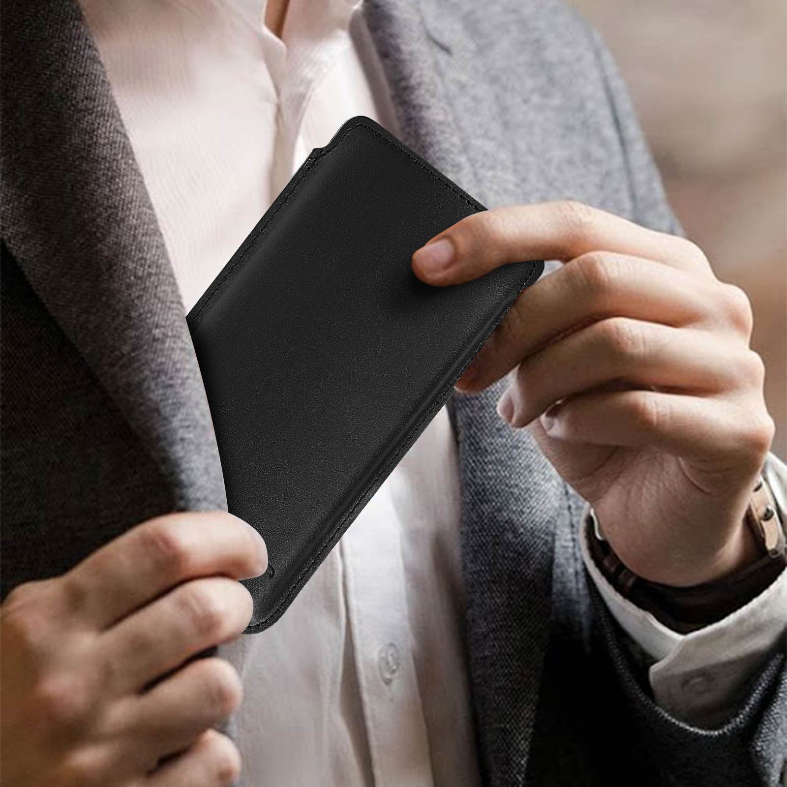 Una custodia per telefono nera è parzialmente in tasca. Una persona indossa una giacca grigia.