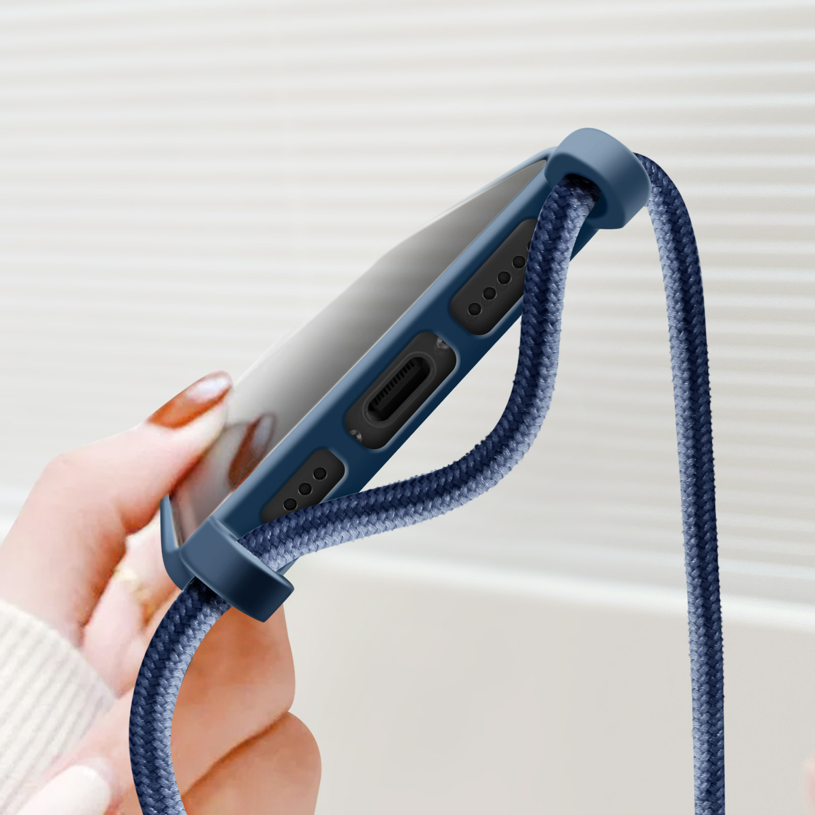 Una mano che tiene una custodia per telefono con un cordino blu. La custodia e il cordino sono blu.