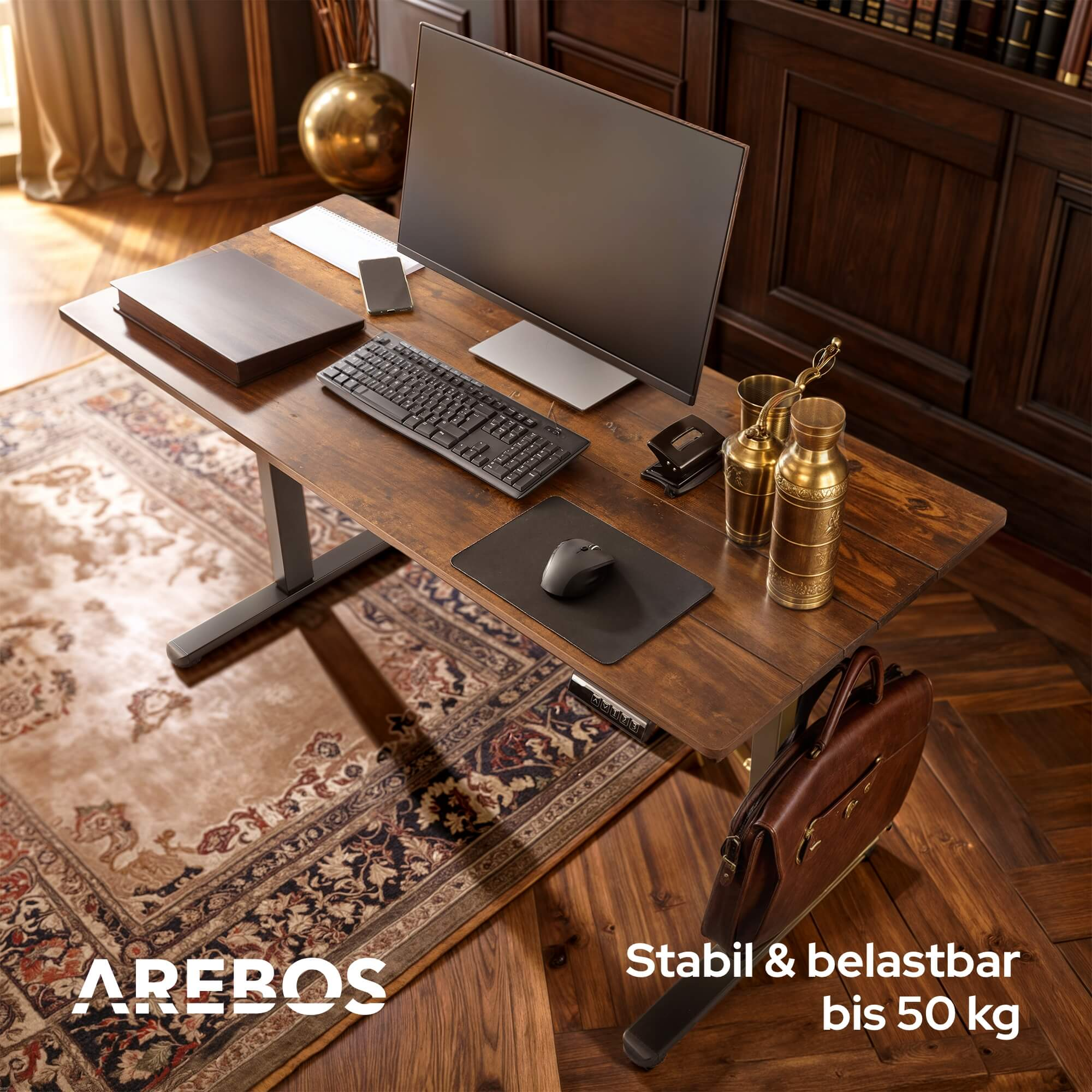 Schreibtisch mit Monitor, Tastatur und Zubehör auf einem Teppich. Eine Tasche hängt an der Seite.