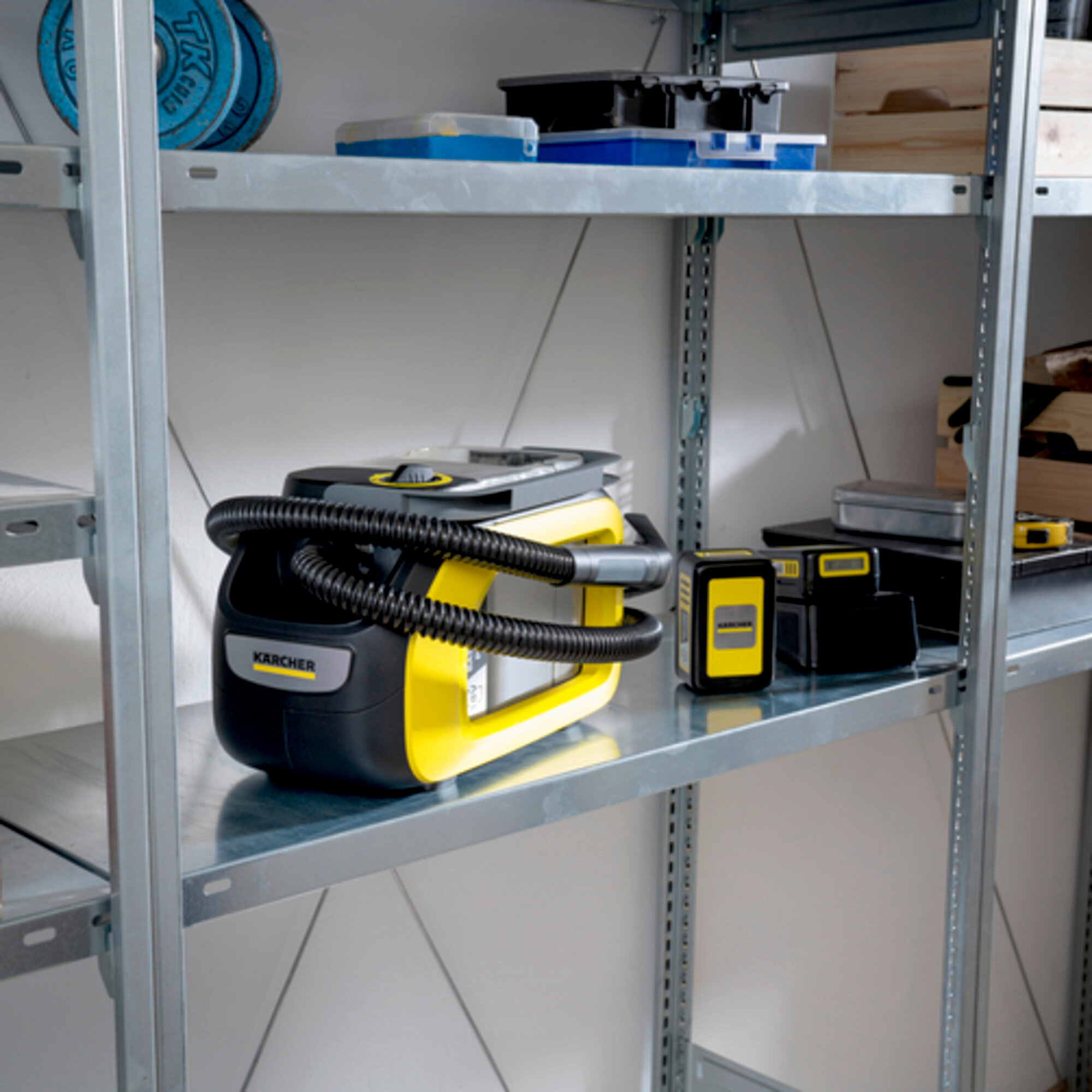 Żółto-czarny odkurzacz Kärcher na półce. Inne narzędzia i pudełka na półkach.