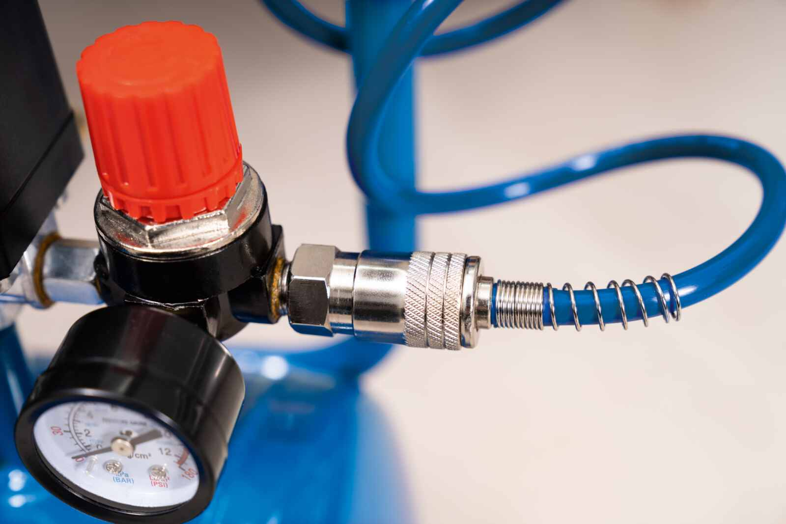 Close-up van de componenten van een luchtcompressor, inclusief een regelaar en een manometer.