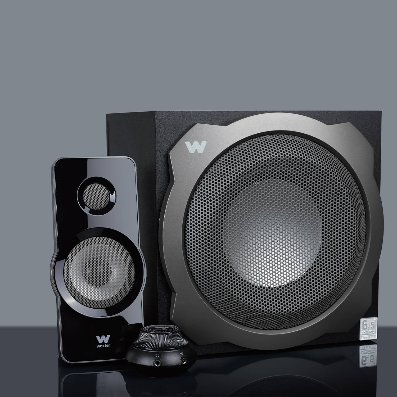 Conjunto de altavoces con subwoofer, altavoz pequeño y mando, todo en negro.