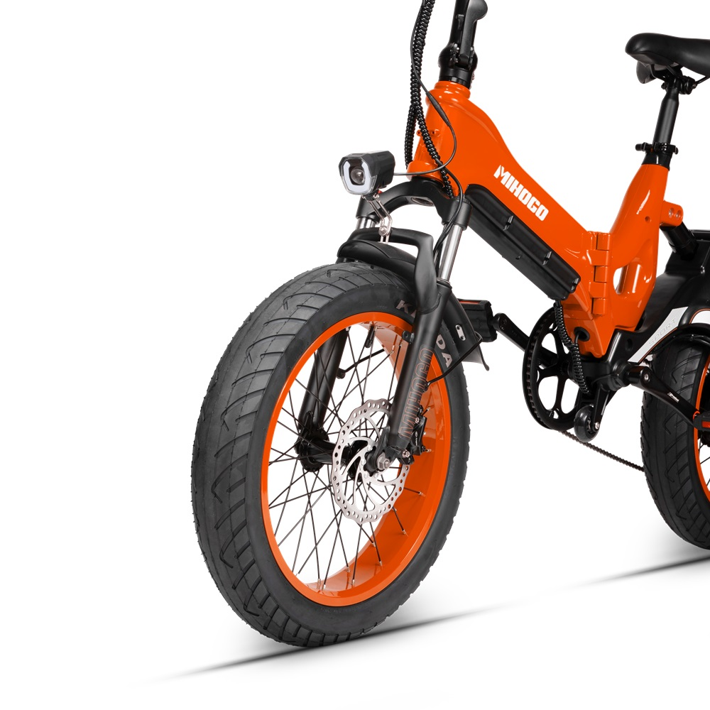 Ein orangefarbenes Elektrofahrrad. Das Vorderrad und die Gabel sind sichtbar. Schwarzer Reifen mit orangefarbener Felge. Weißer Hintergrund.