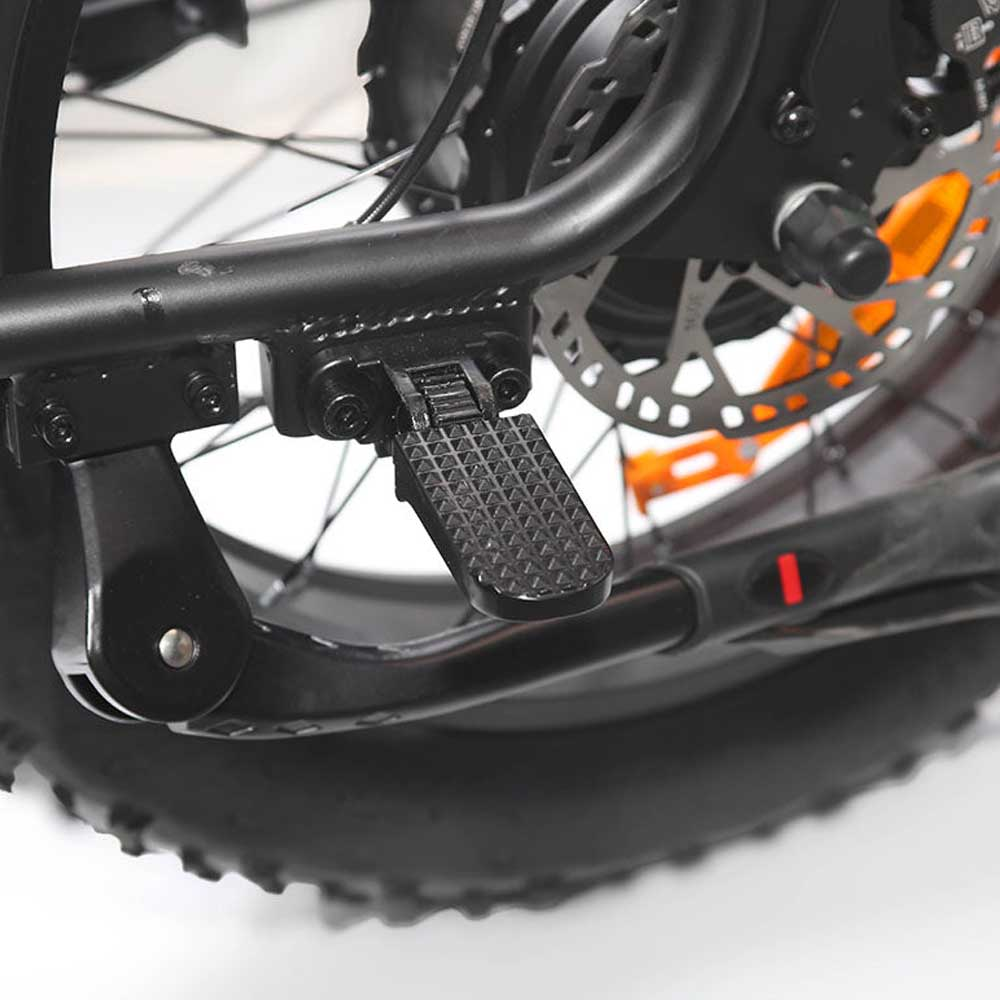 Primer plano de un reposapiés de bicicleta eléctrica negra. El reposapiés está plegado. Freno de disco visible.