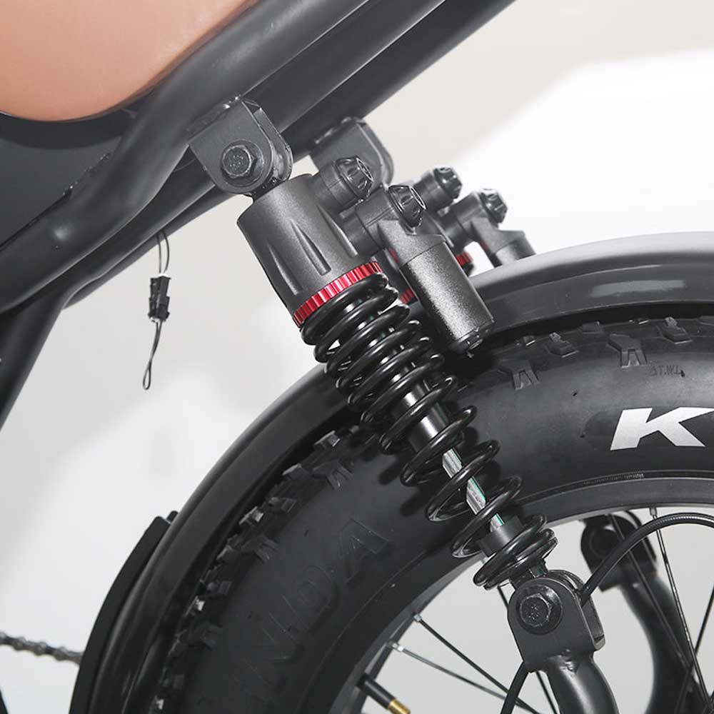 Primer plano de la suspensión trasera de una bicicleta negra. Muestra el muelle, el amortiguador y el neumático.