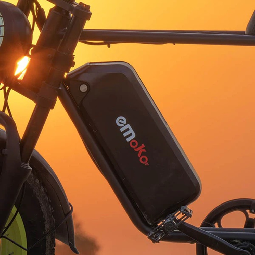 Batería negra montada en una bicicleta. La batería es negra con el logo "emoke", sobre un cielo naranja.