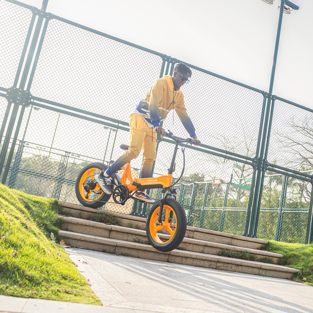 Eine Person fährt mit einem orangenen Fahrrad eine Treppe in einem Park hinunter, trägt einen gelben Anzug.