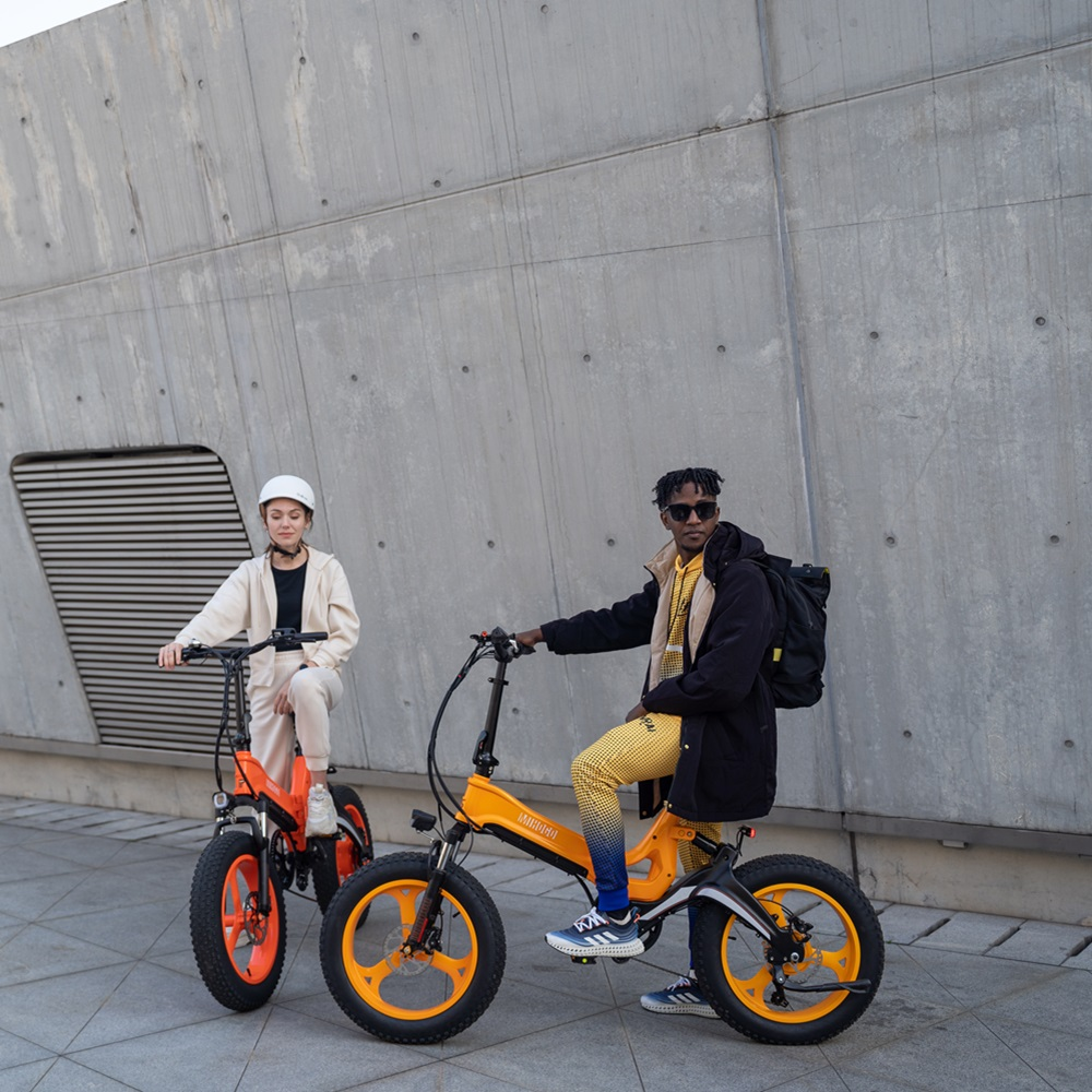 Zwei Personen mit E-Bikes stehen neben einer Betonmauer.