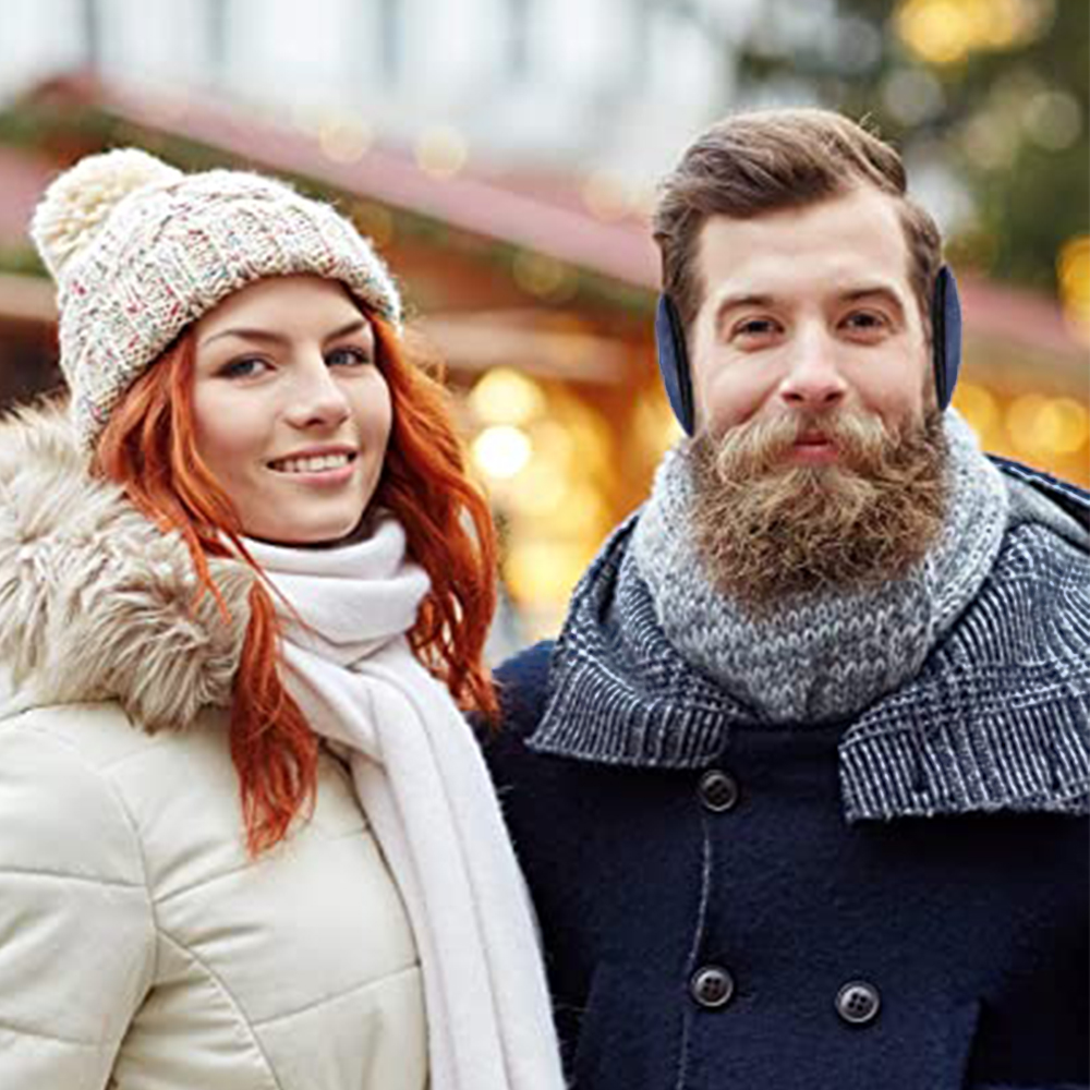Ein Paar mit Wintermützen und Ohrenschützern. Der Mann hat einen Bart. Hintergrund mit Lichtern.