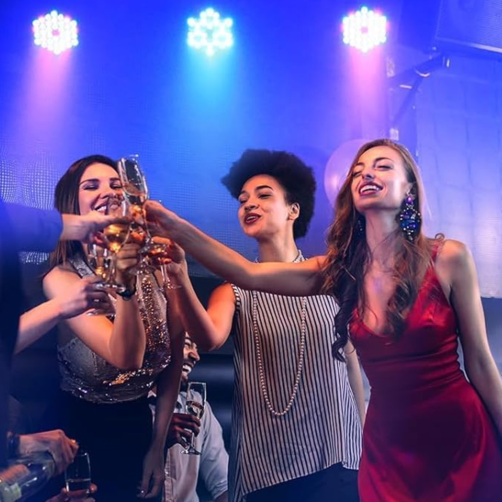 Leute stoßen mit Champagner in einem Club an. Die Szene wird mit blauem und rosa Licht beleuchtet.