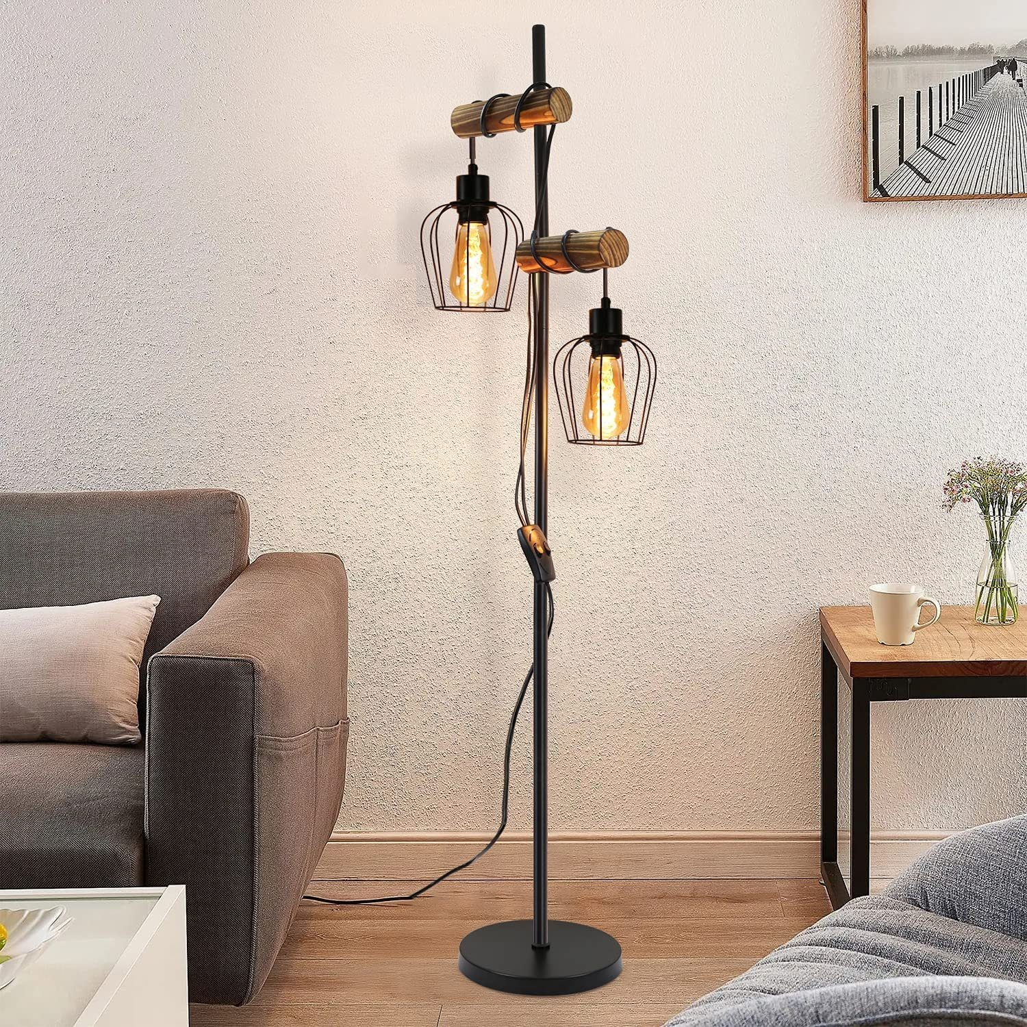 Una lampada da terra con due lampadine a gabbia e supporti in legno, in un soggiorno.