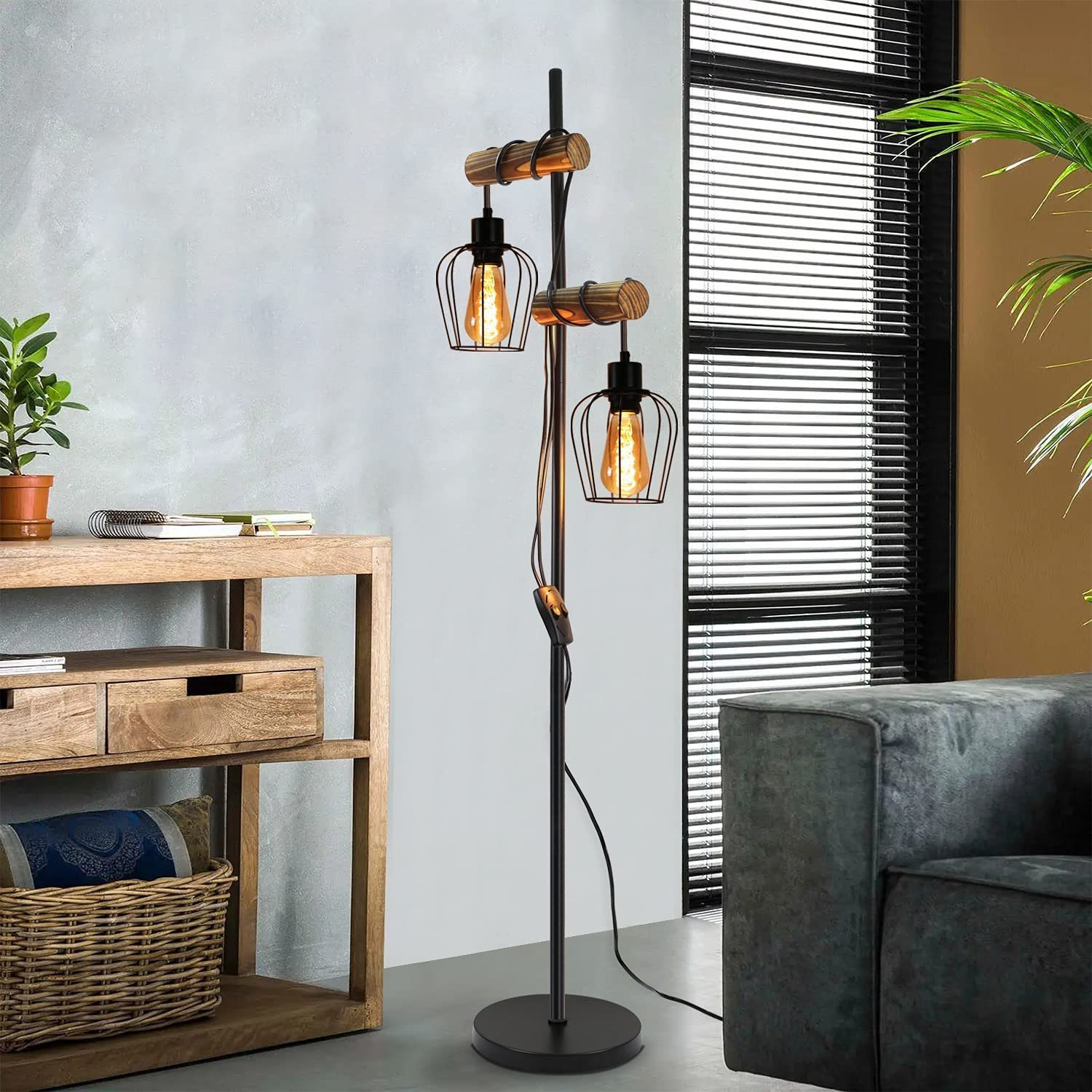 Una lampada da terra con due lampadine a gabbia e supporti in legno, in un soggiorno.