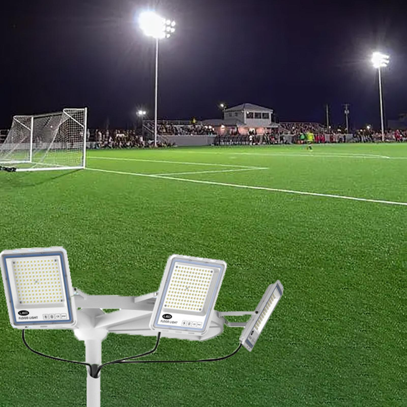 Ein Fußballfeld bei Nacht wird von Stadionlichtern beleuchtet. Ein Licht befindet sich im Vordergrund.