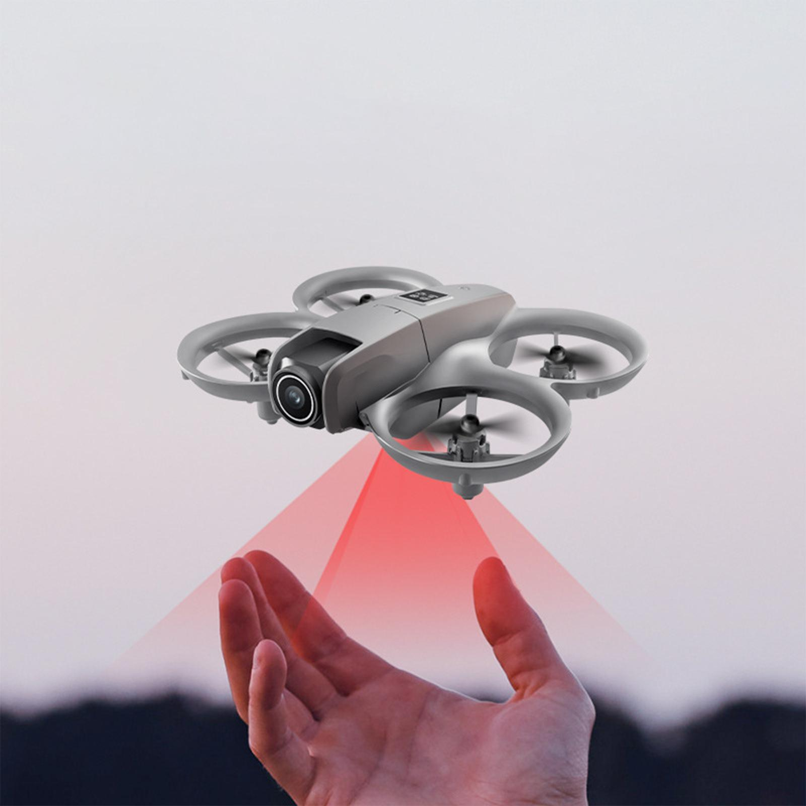 Eine Drohne schwebt, ein roter Laserstrahl wird auf eine hochgereckte Hand projiziert.