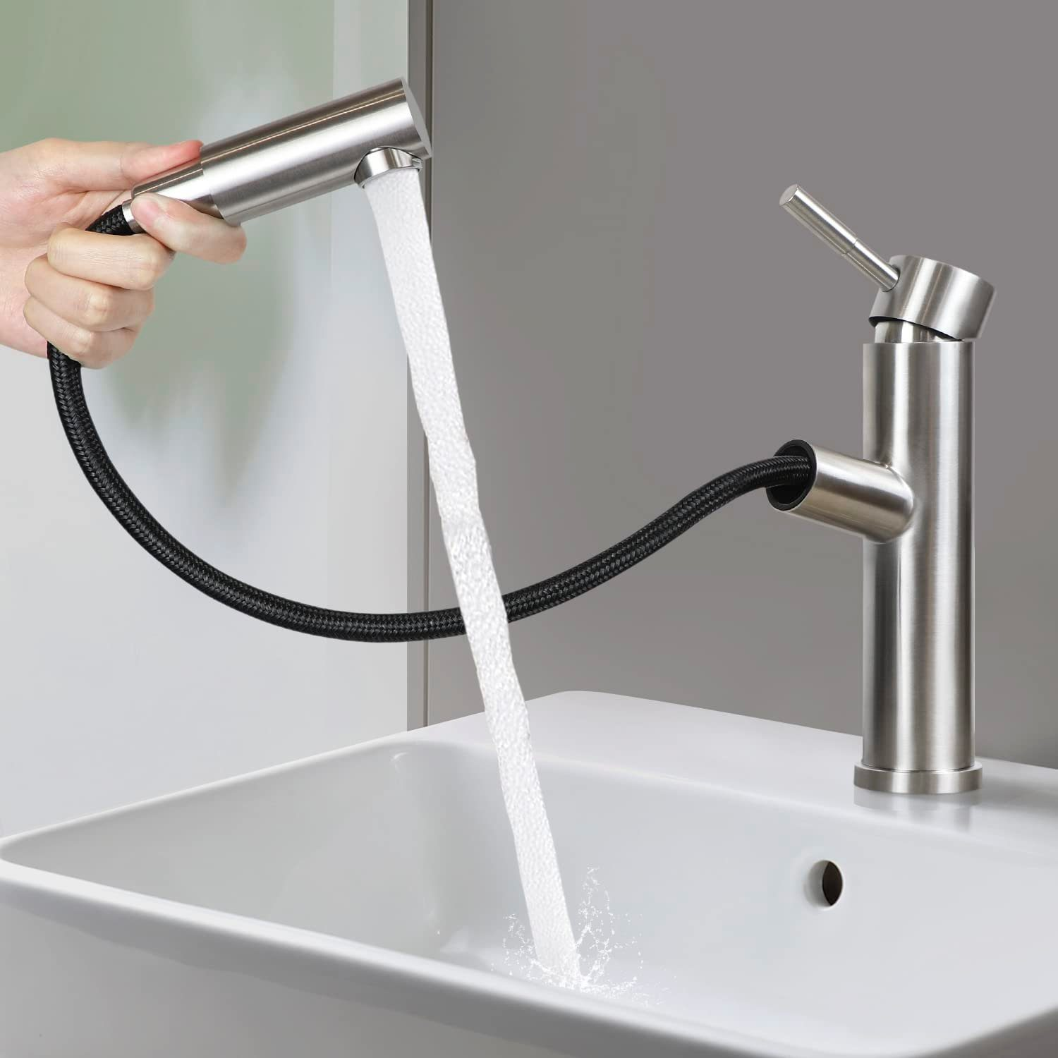 Eine Hand sprüht Wasser aus einer ausziehbaren Armatur. Die Armatur ist Edelstahl, Wasser fließt ins Waschbecken.