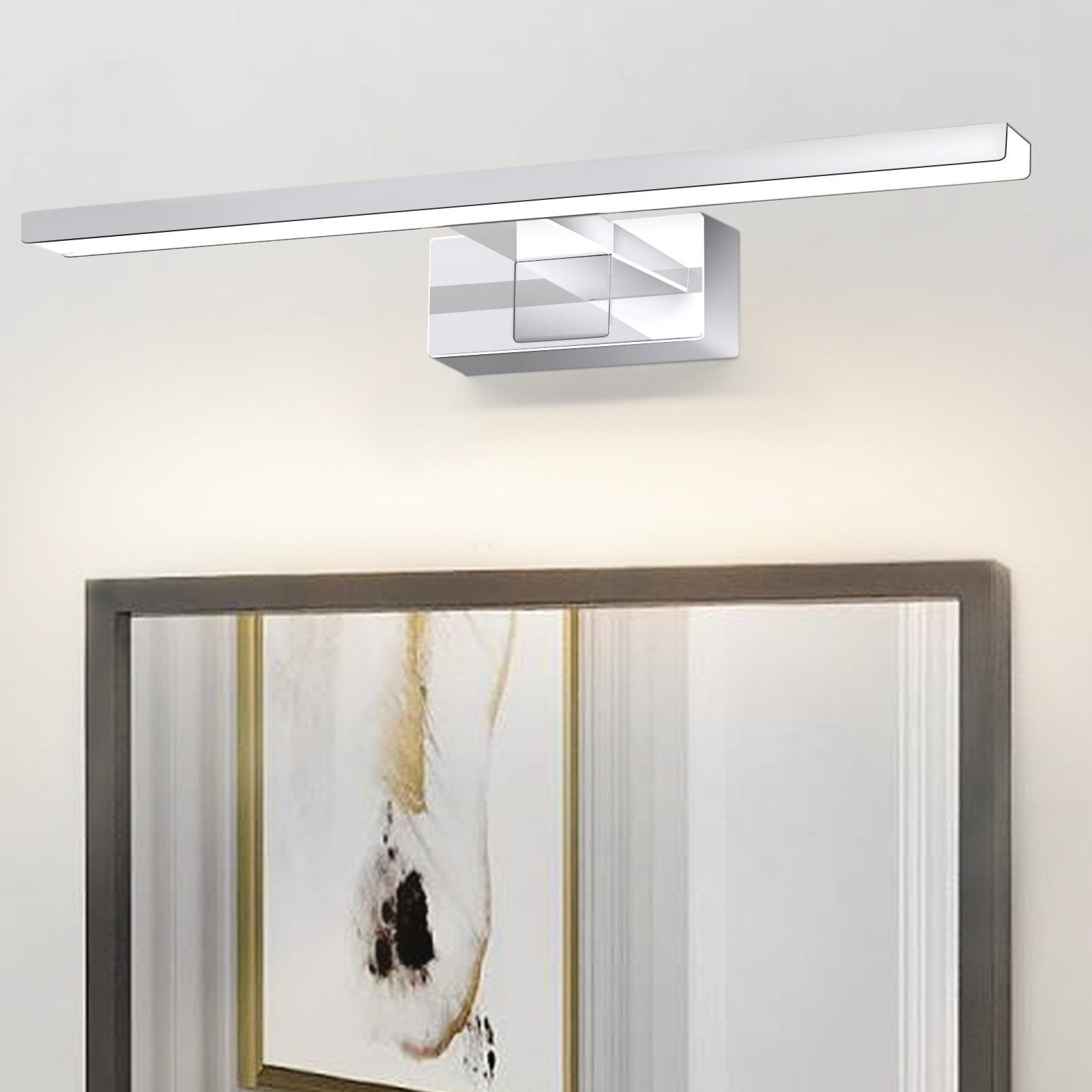 Moderna lampada da parete argentata sopra un'opera d'arte incorniciata. Sfondo parete bianco. La luce è rettangolare con un dettaglio quadrato.