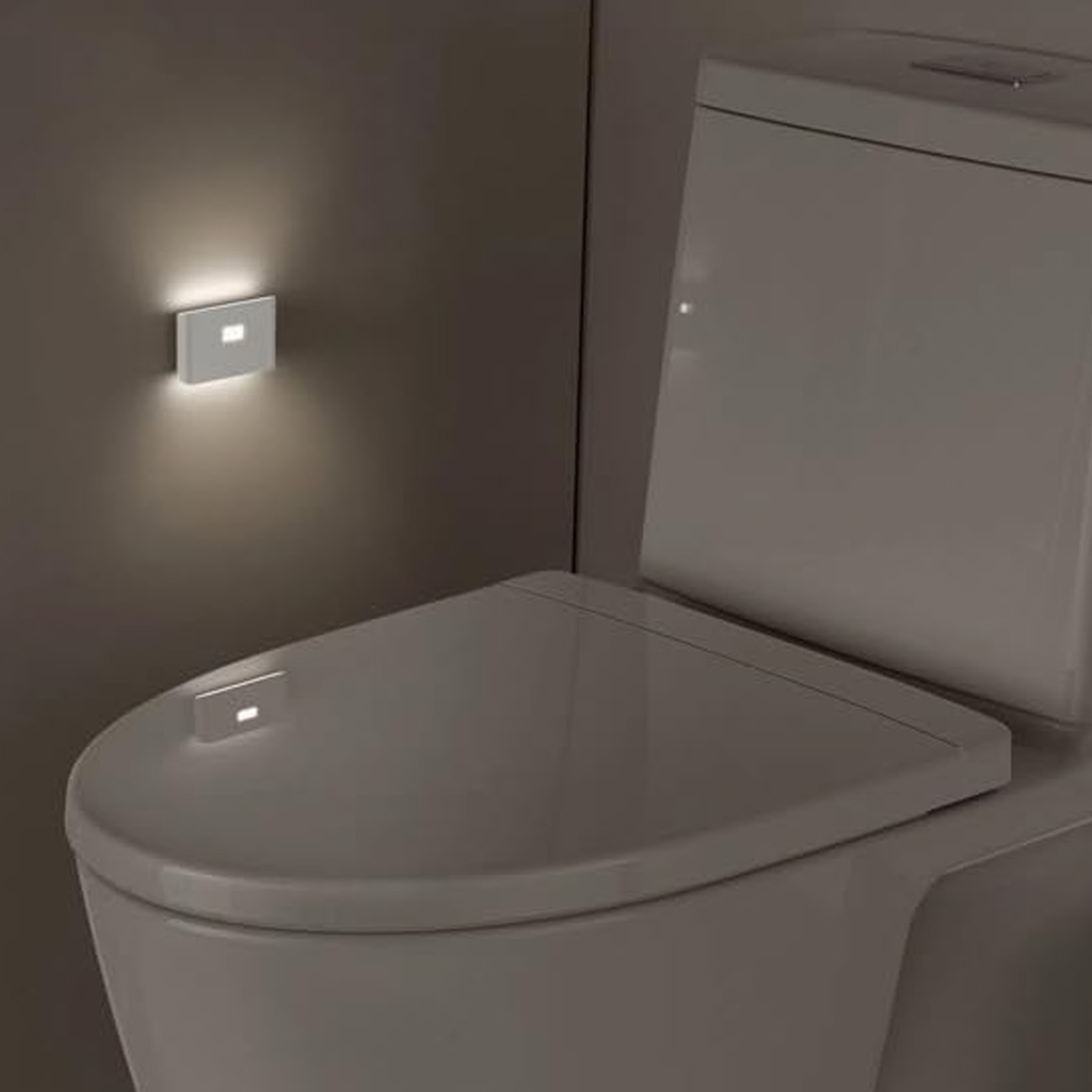 Eine weiße Toilette mit einem kleinen Licht an der Wand und auf dem Toilettendeckel. Der Raum ist dunkel.