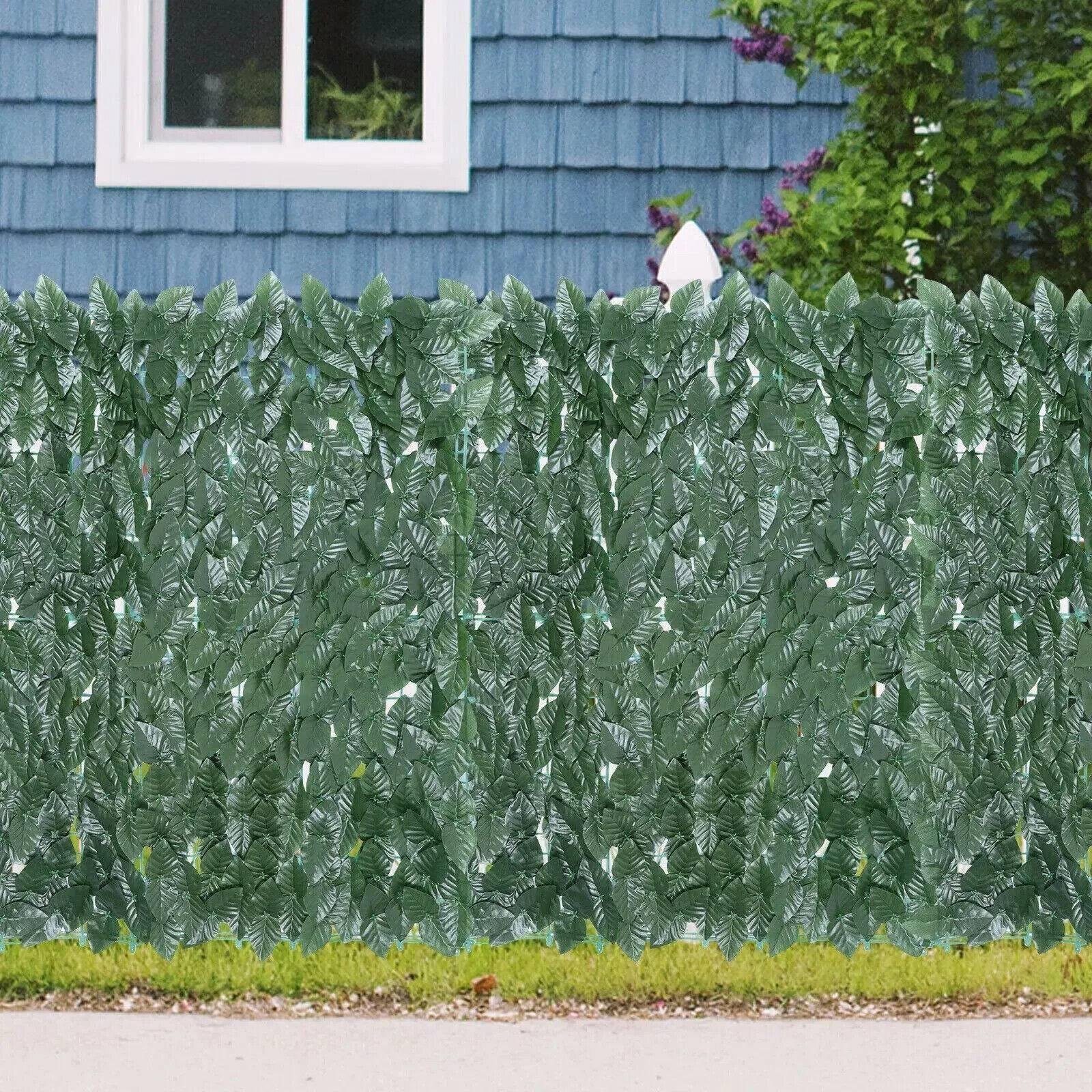 Grüner Blätterzaun mit Haus im Hintergrund.