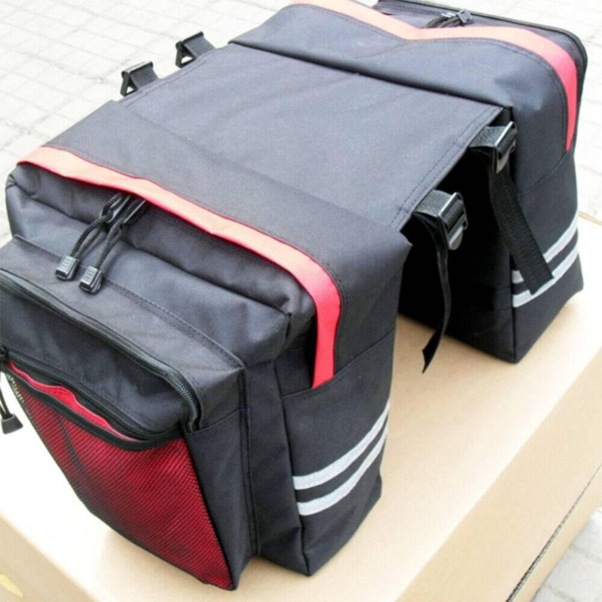 Schwarze Fahrrad-Gepäckträgertaschen mit roten und weißen Akzenten, auf Pappe.