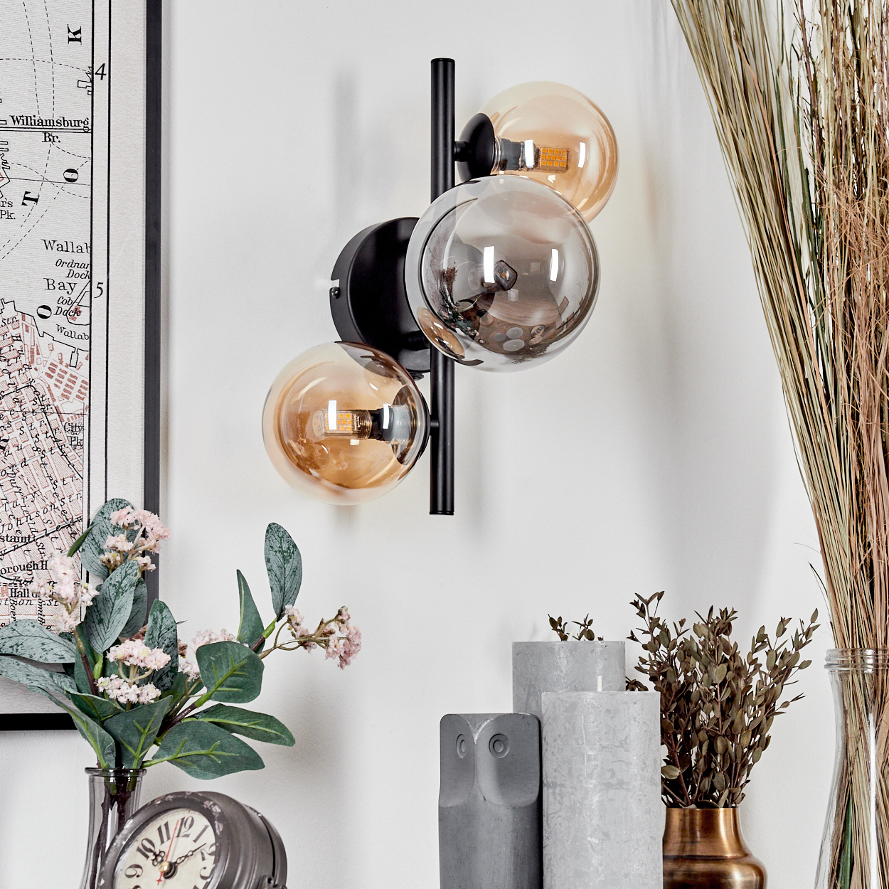 Innenraum mit Wandkunst, Blumen und einer modernen Wandlampe mit Kugeln.
