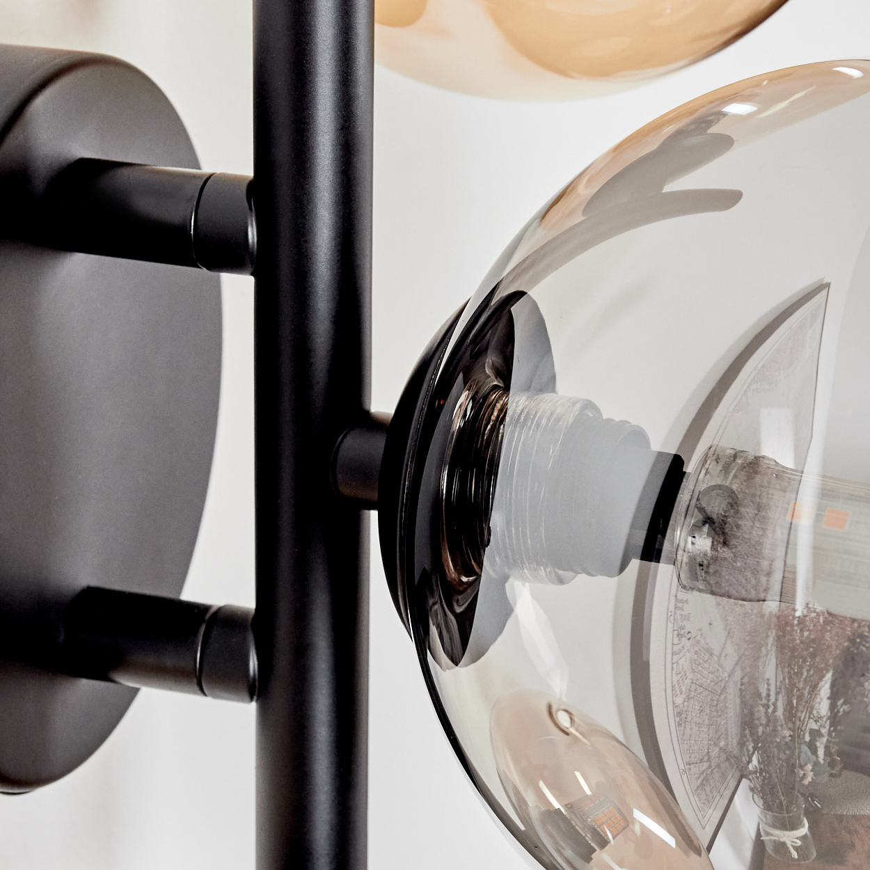 Nahaufnahme einer Dreilampen-Leuchte. Die Lampe hat einen schwarzen Stiel und drei Glaskugeln.