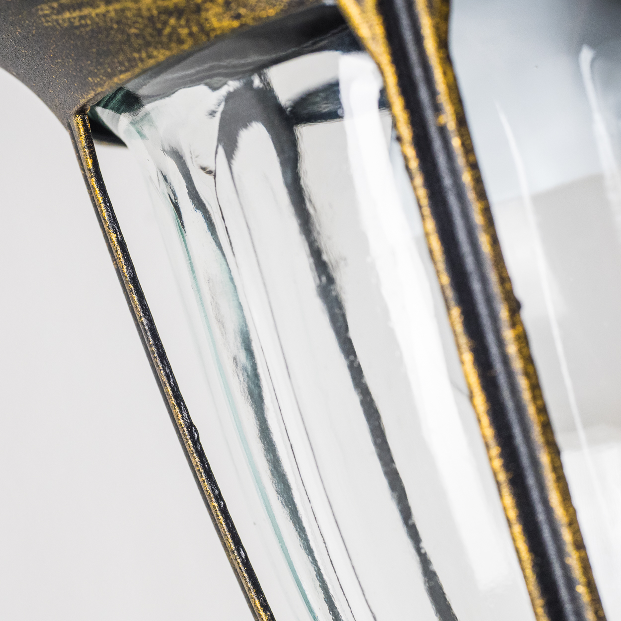 Nahaufnahme einer Glasscheibe mit schwarzem und goldenem Besatz, wodurch eine strukturierte und detaillierte Optik entsteht.
