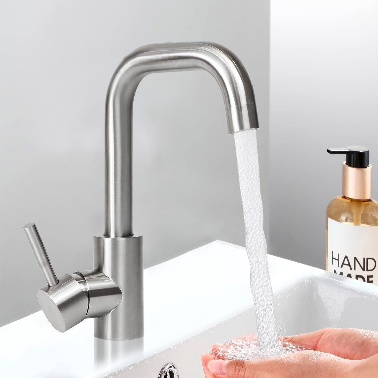 Eine Küchenarmatur aus Edelstahl, aus der Wasser in ein weißes Waschbecken fließt.