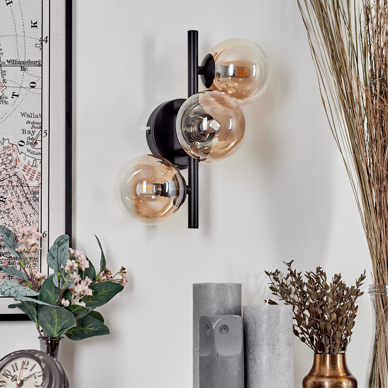 Eine Wandlampe mit schwarzem Sockel und Arm, der einen runden, bernsteinfarbenen Glasschirm hält.