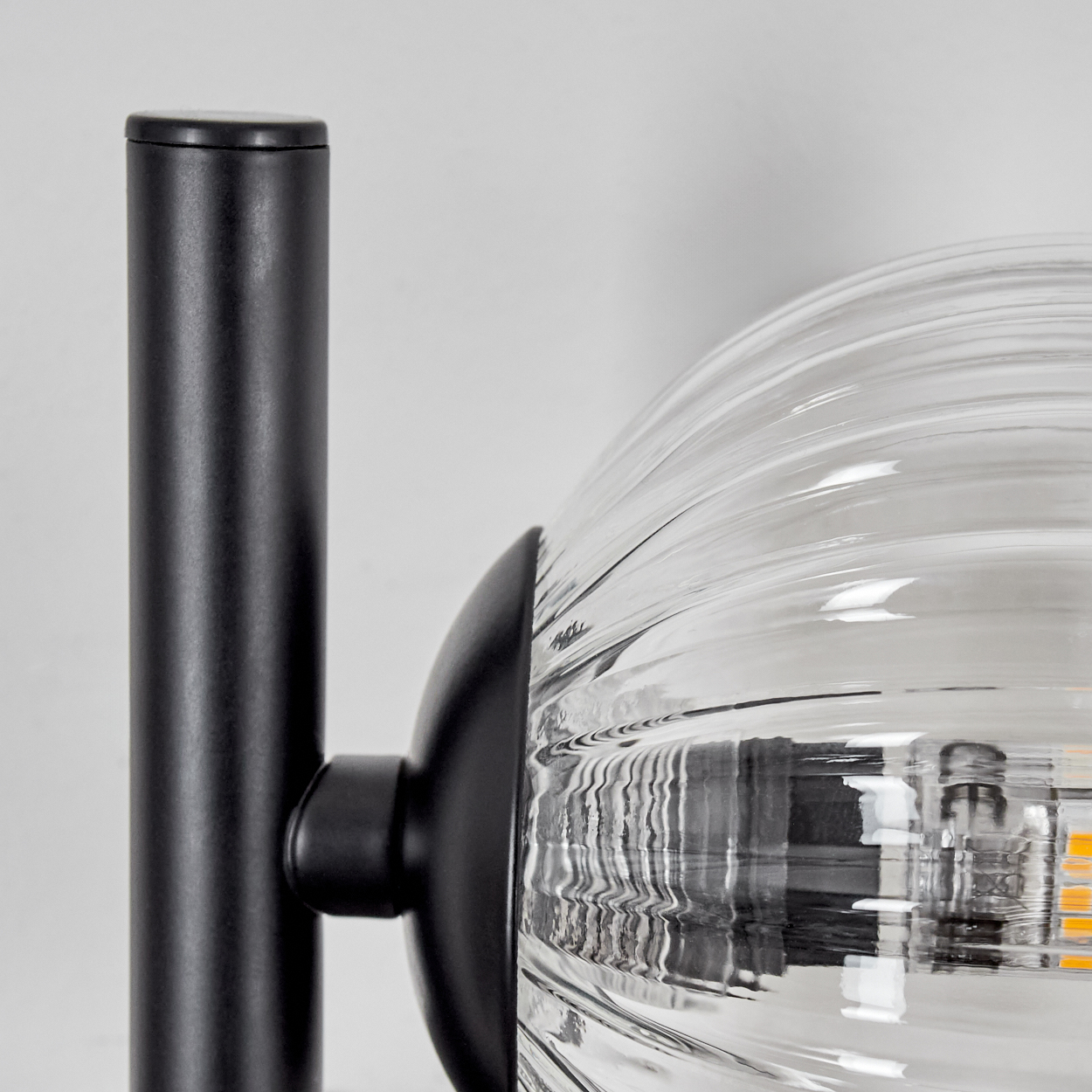 Schwarze Lampe mit einer klaren Glaskugel. Die Lampe befindet sich auf weißem Hintergrund.