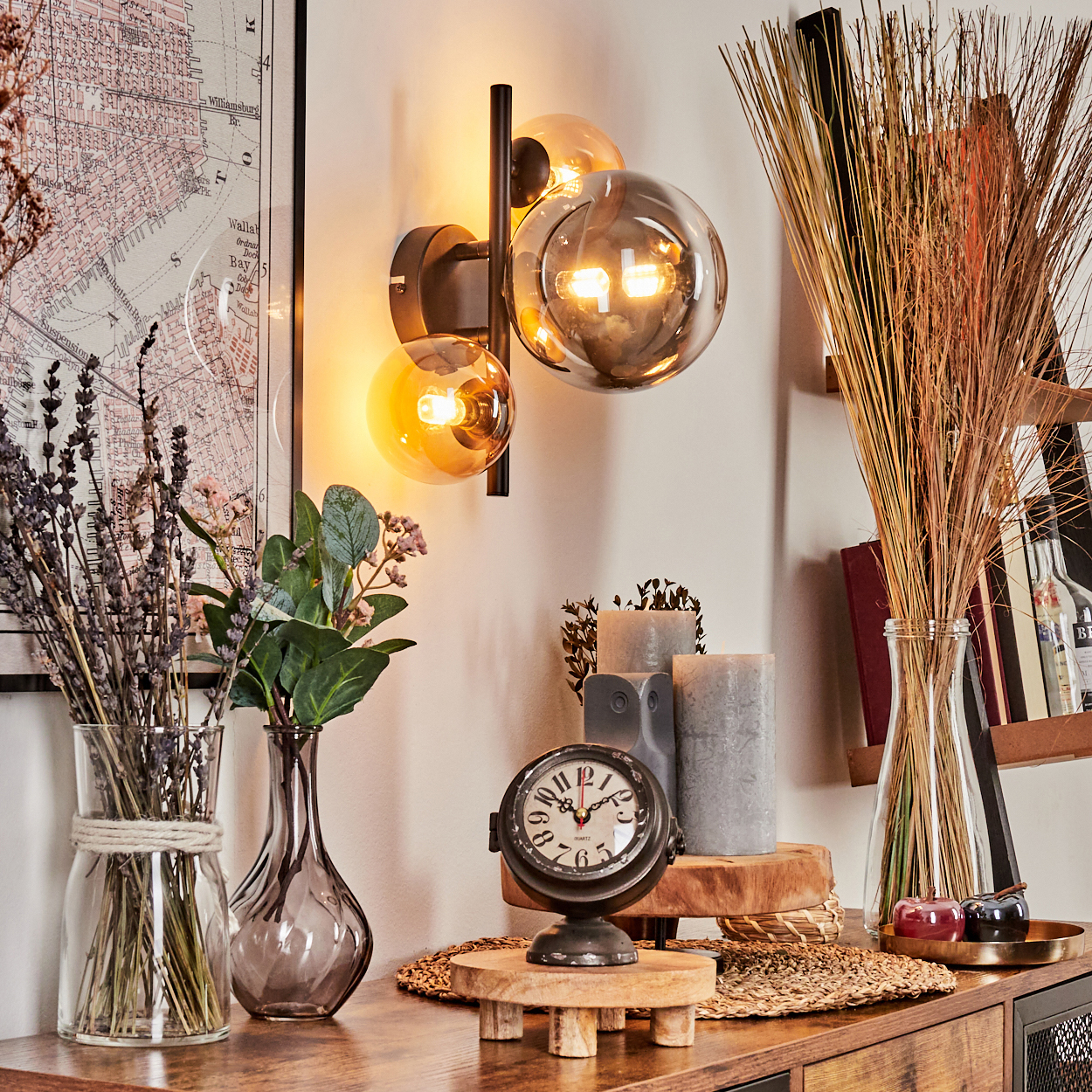 Wandlampe mit drei Glaskugeln. Bernstein- und graue Kugeln. Deko mit Uhr, Pflanzen und Kerzen.