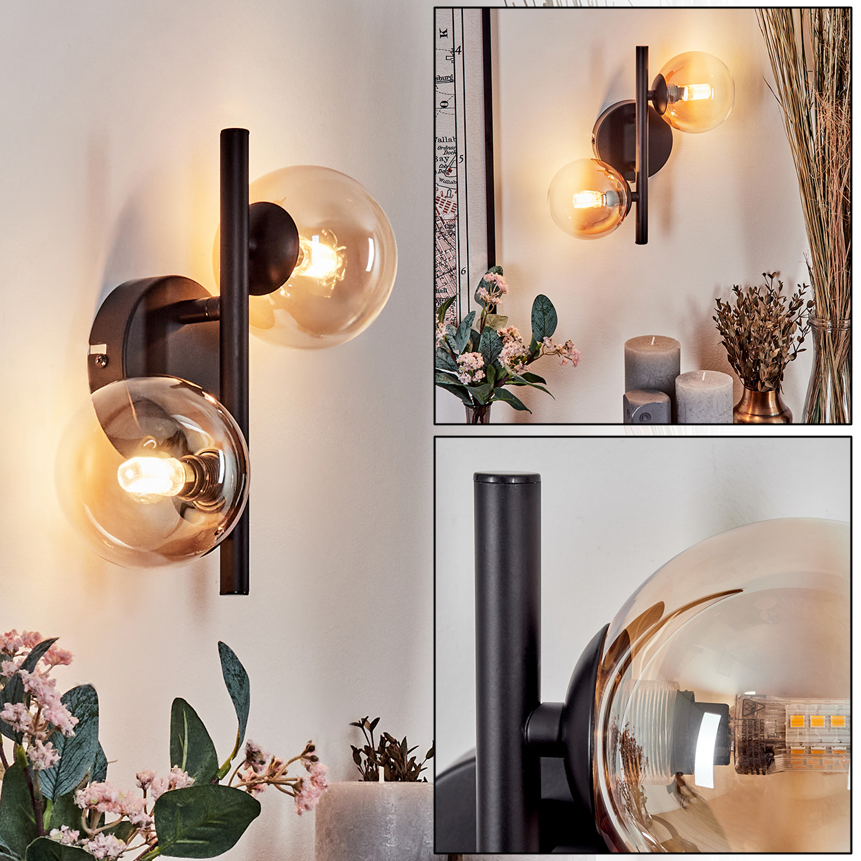 Moderne Wandleuchte mit zwei bernsteinfarbenen Glaskugeln, schwarzem Rahmen, vor weißer Wand mit Deko.