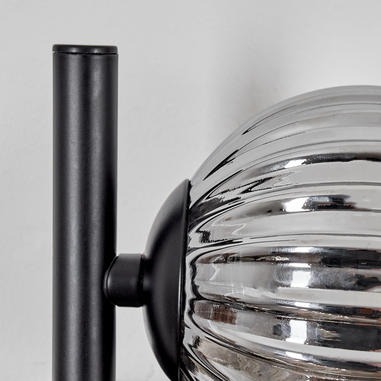 Nahaufnahme einer modernen schwarzen und verchromten Lampe mit geripptem Glaskugel.