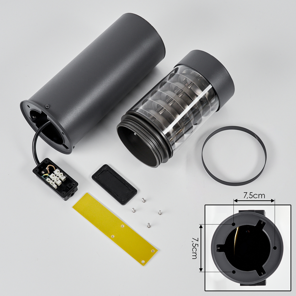Zerlegte Komponenten einer dunkelgrauen Außenlampe: Gehäuse, Glas, elektrische Komponenten und Befestigungsmaterial.