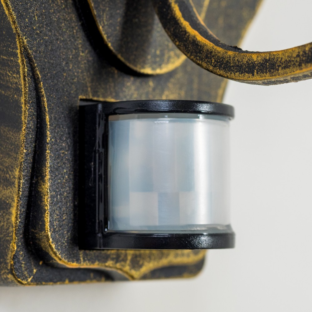Nahaufnahme des Sensors an einer bronzenen Außenwandleuchte vor weißem Hintergrund.