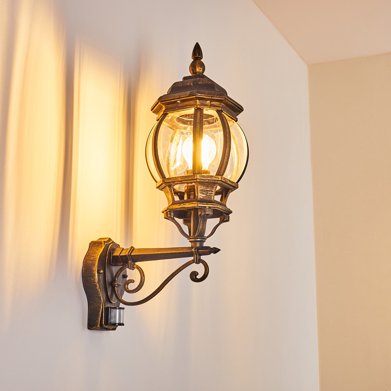 Außenwandleuchte mit Glaskugel und klassischem Design, an weißer Wand montiert.